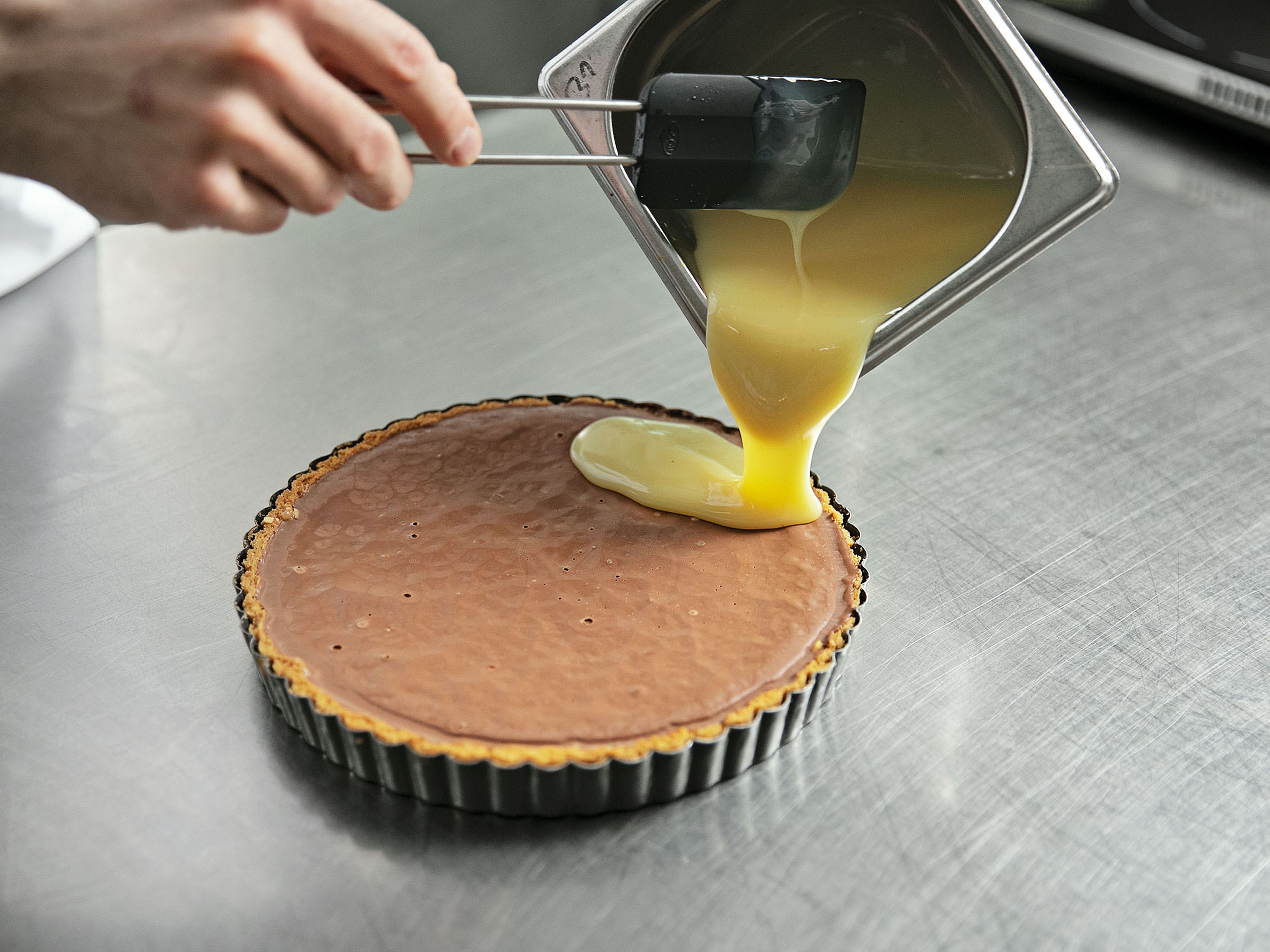 Remove cooled tart from the fridge and distribute the ganache on it. Allow to cool for approx. 4 hrs. Chop the caramelized hazelnuts and set aside. Remove tart from the fridge spread orange filling onto the tart.