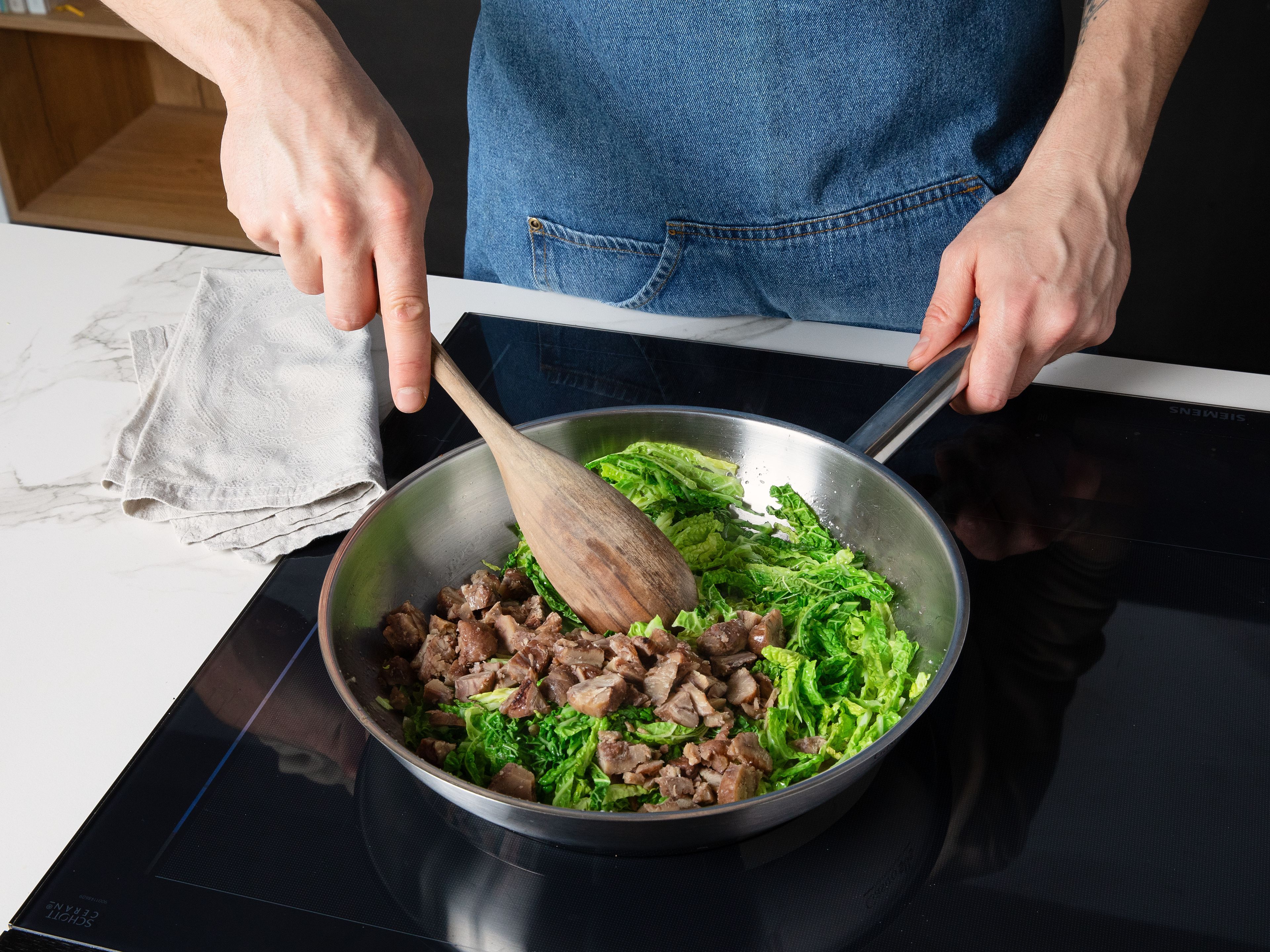 In derselben großen Pfanne Olivenöl erhitzen, den Wirsing darin ca. 5–7 Min. anbraten, bis er weich und leicht gebräunt ist. Den Knoblauch und die gehackten Maronen hinzufügen und kurz mit anschwitzen. Mit Salz und Pfeffer abschmecken.