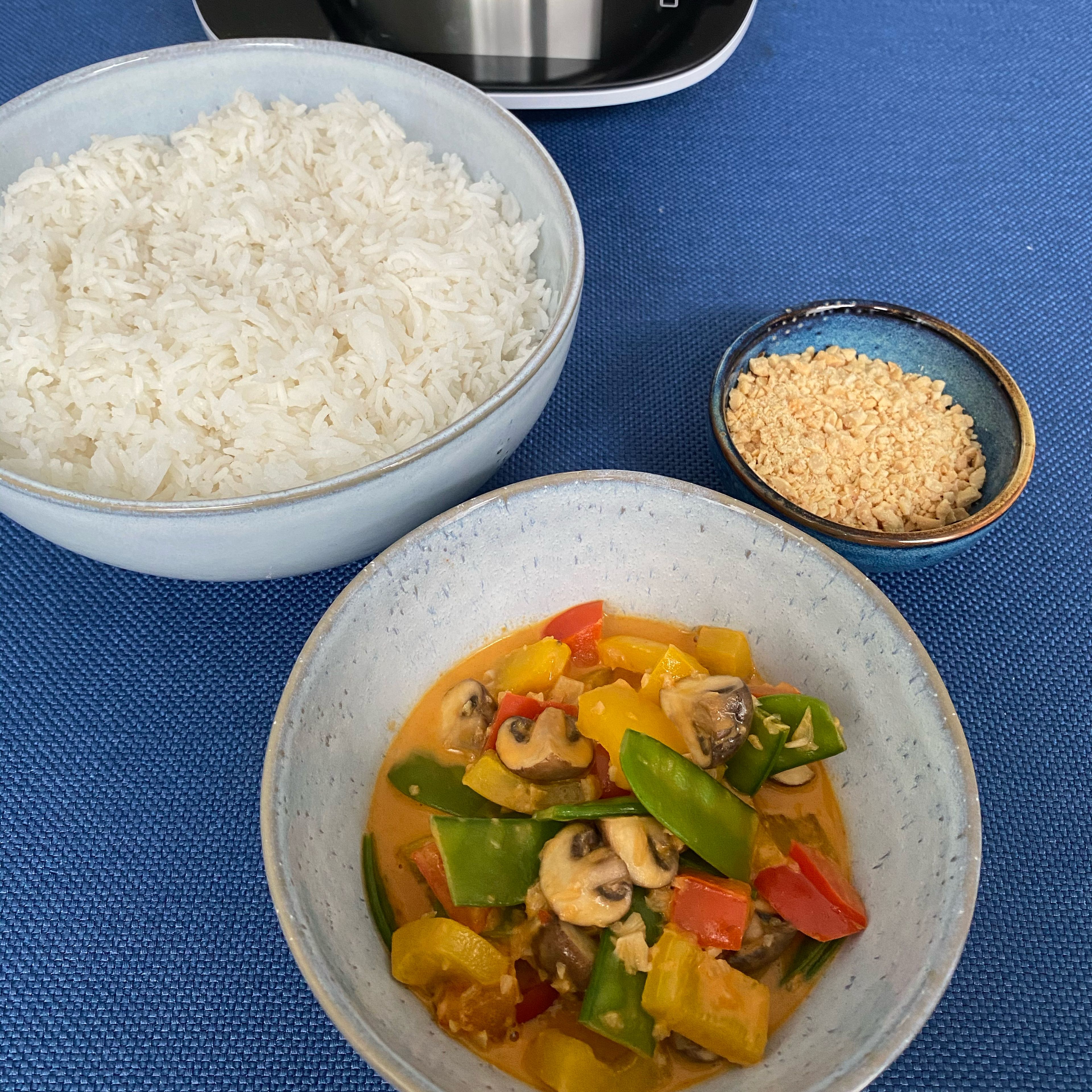 Das Universalmesser entfernen und den Reis mit dem Curry und den gerösteten Erdnüssen servieren.