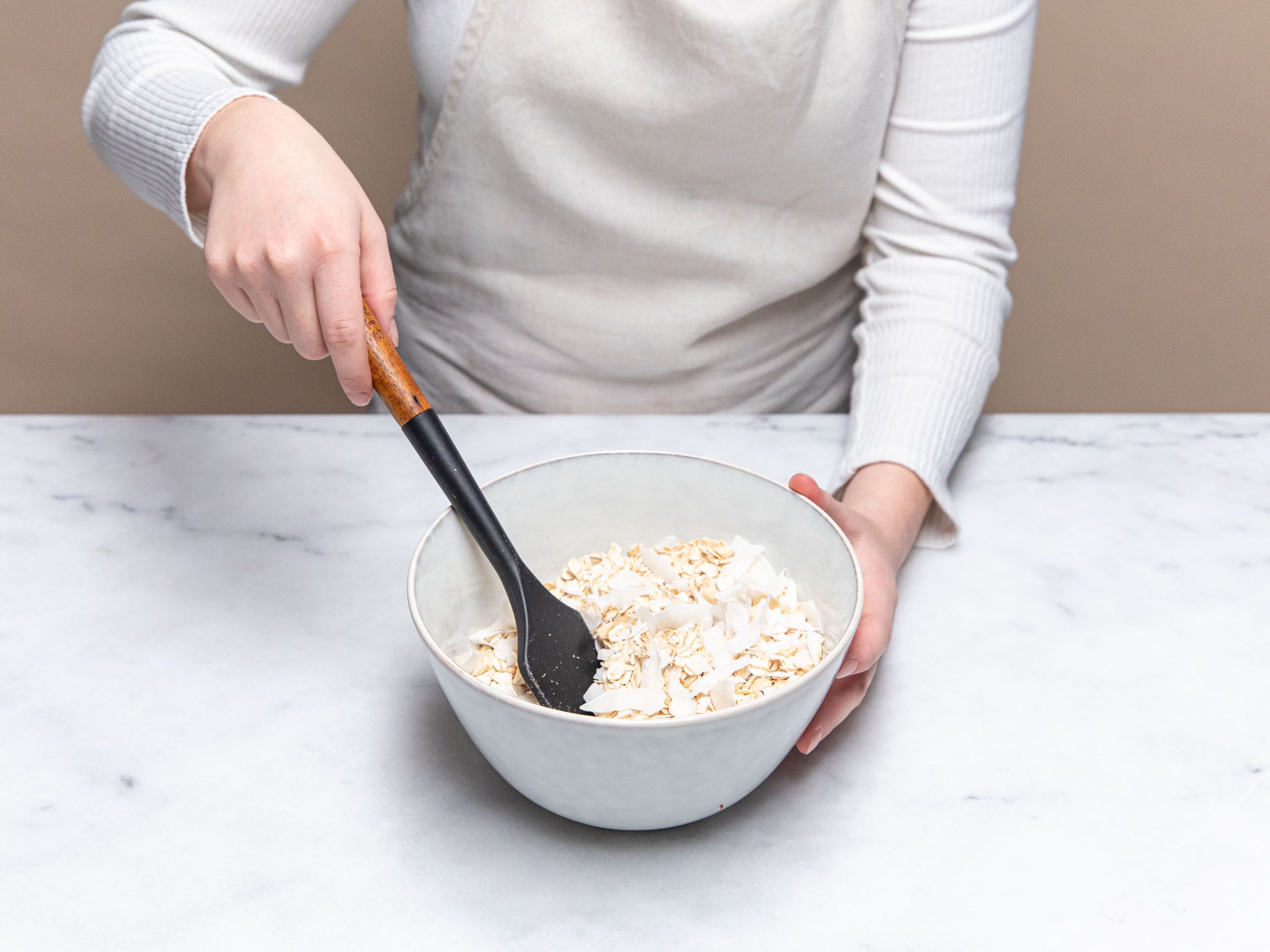Mix oats, chopped almonds, coconut flakes and salt in a bowl. Add olive oil and maple syrup to the granola mixture. Mix everything well together until all the dry ingredients are glazed with the syrup and oil.
