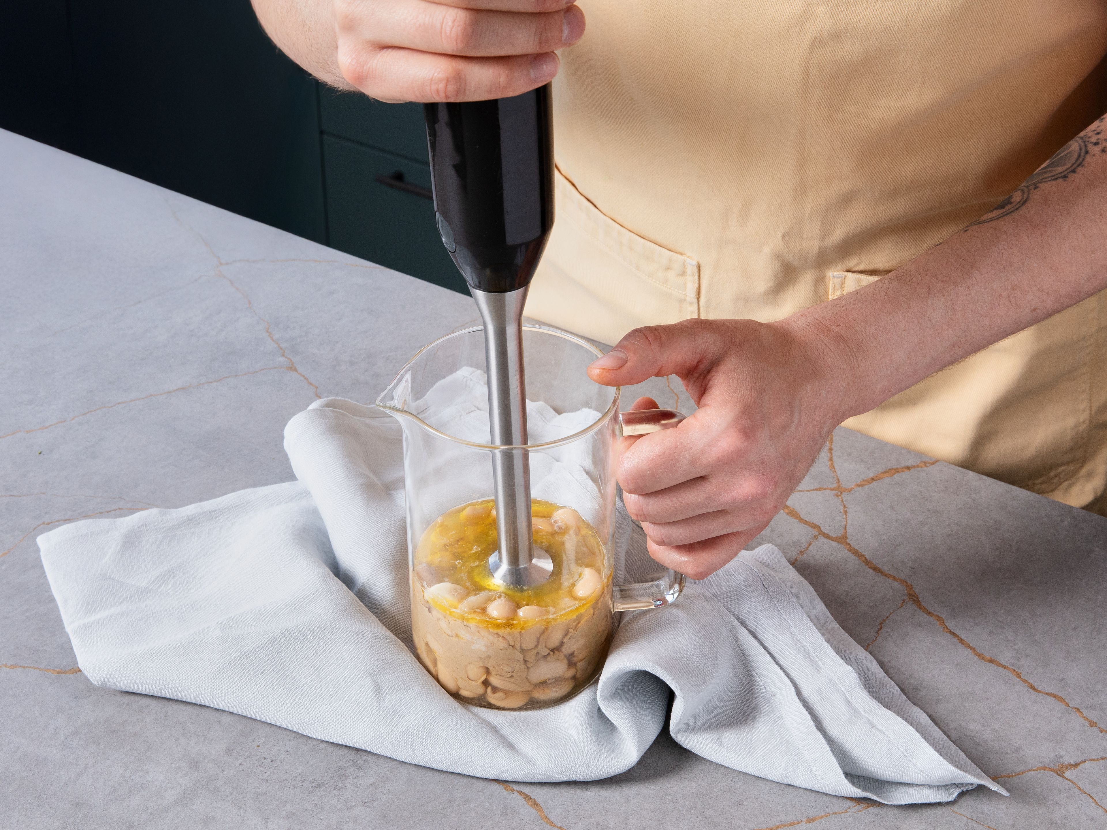 Zest and juice lemon. Peel half the garlic. Add remaining beans to a blender with tahini, garlic, aquafaba (or cold water), and some salt. Blend into a smooth, creamy hummus. If it’s too thick, add more aquafaba or water. Season with salt and lemon juice to taste.