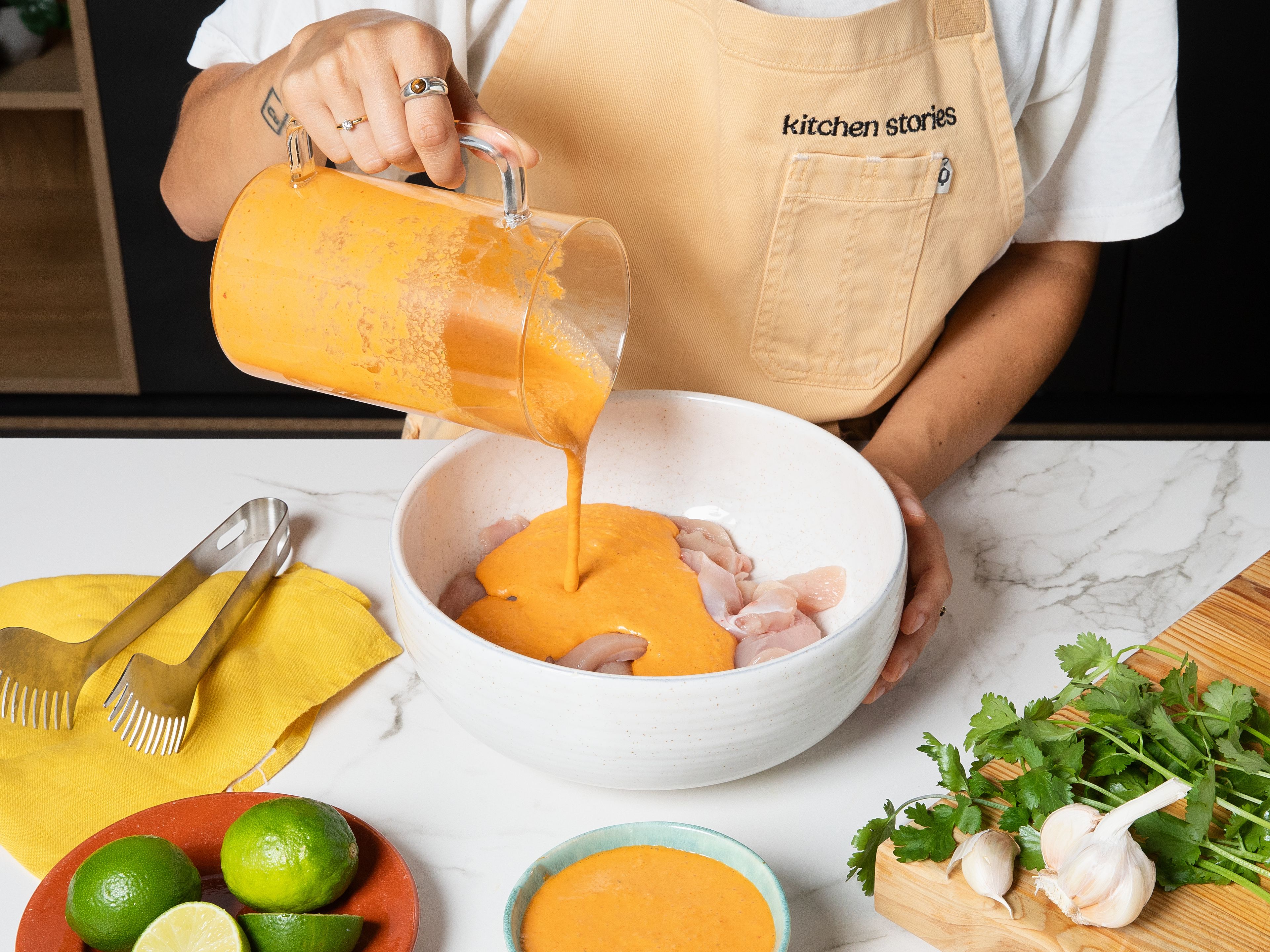 Hähnchenbrust in Streifen schneiden. Korianderblätter abzupfen und zum Garnieren beiseitelegen, die Korianderstiele grob hacken. Knoblauch und Ingwer schälen. Limette auspressen. Currypaste, Kokosmilch, Knoblauch, Ingwer, Korianderstiele, braunen Zucker, Fischsauce und Limettensaft in einem Mixer zu einer glatten Marinade pürieren. Ein Drittel der Marinade für später beiseitestellen. Den Rest in eine große Schüssel geben, das Hähnchen hinzufügen und alles gründlich vermengen. Abgedeckt ca. 1 Std. im Kühlschrank marinieren lassen.