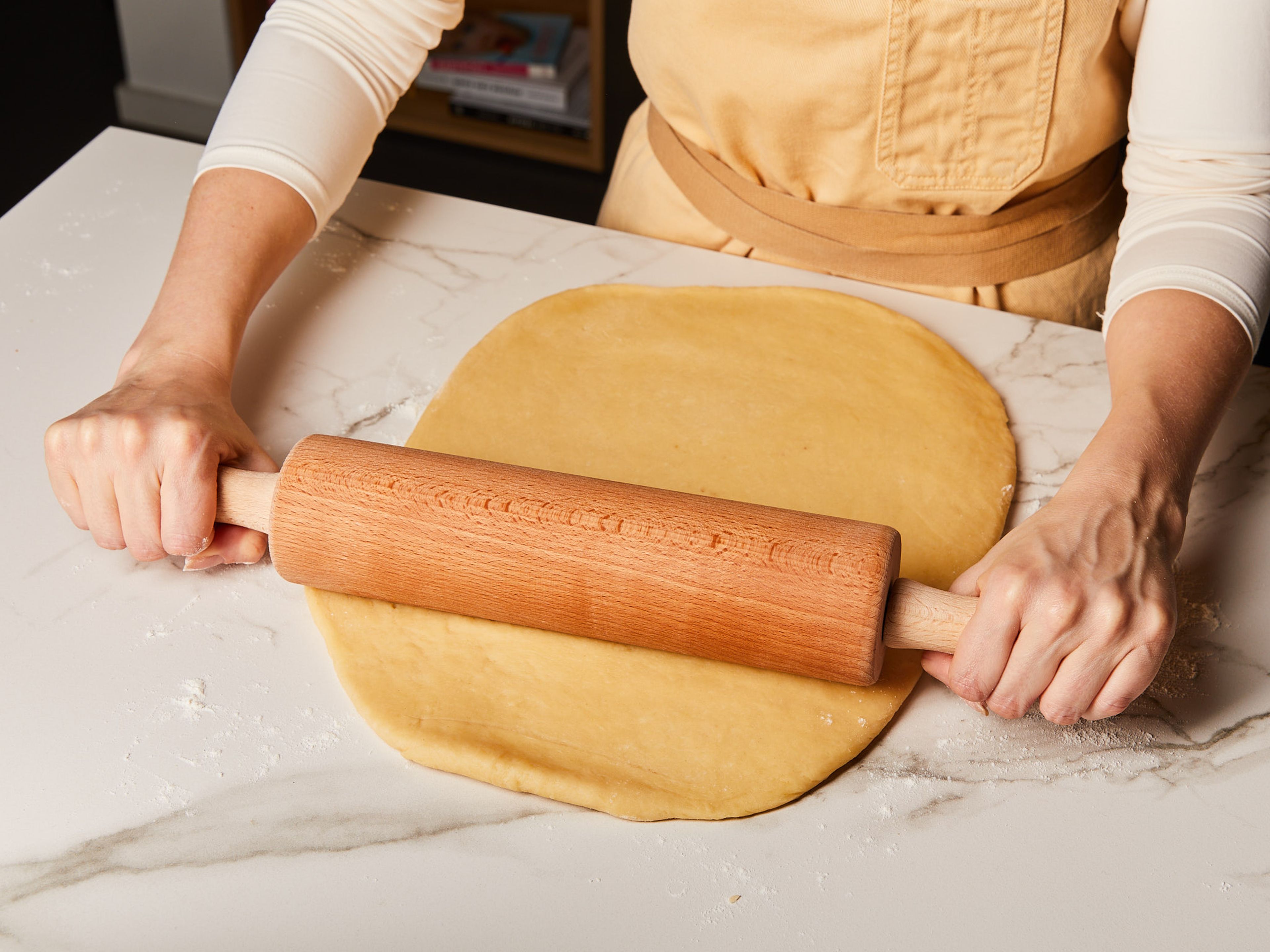 Den Ofen auf 180°C vorheizen. In einer Schüssel gemahlenen Zimt, Muskatnuss und einen Teil des Zuckers mischen. Ein Backblech oder eine Backform mit Butter einfetten. Den Teig auf einer leicht bemehlten Fläche kurz durchkneten, bis er glatt ist, und dann so ausrollen, dass er auf das Backblech passt.