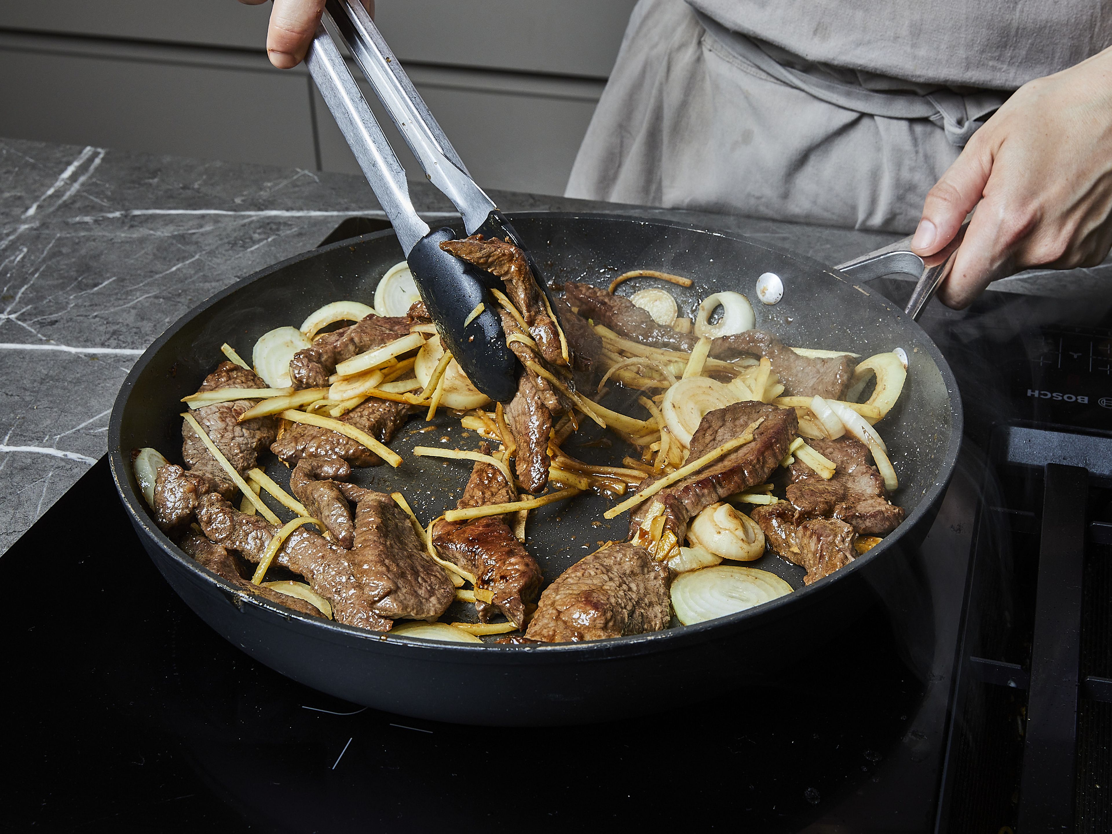 Heat some oil in a pan until very hot. Add beef strips and fry until they brown all over. Add ginger and onion. Fry until onions slightly caramelize on the edges.