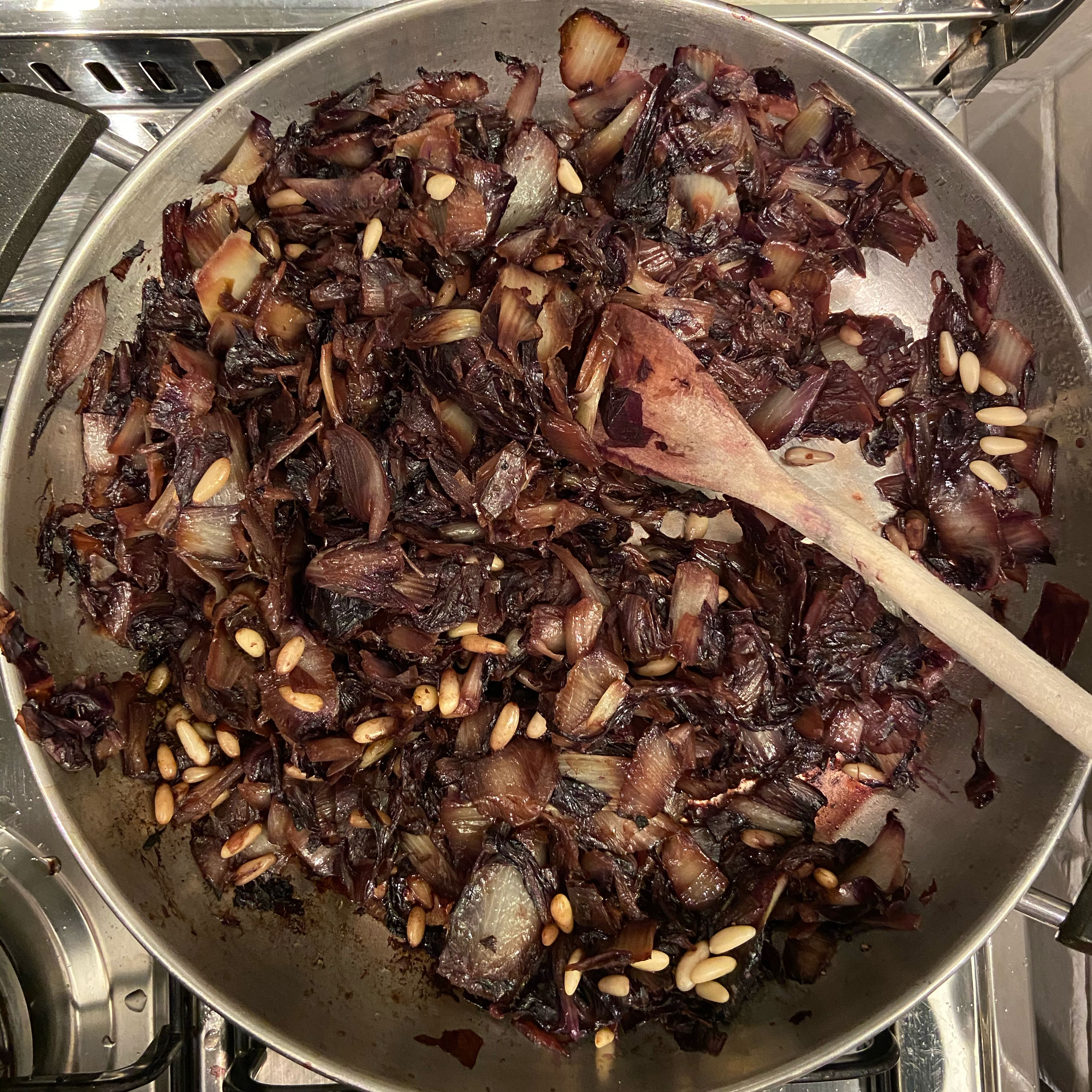 Add olive oil and a sliced onion to a frying pan; cook over medium heat until the onions are soft and golden. Then add the finely cut radicchio, pine nuts and salt. After a couple of minutes, add the red wine and let everything cook for around 8 minutes.