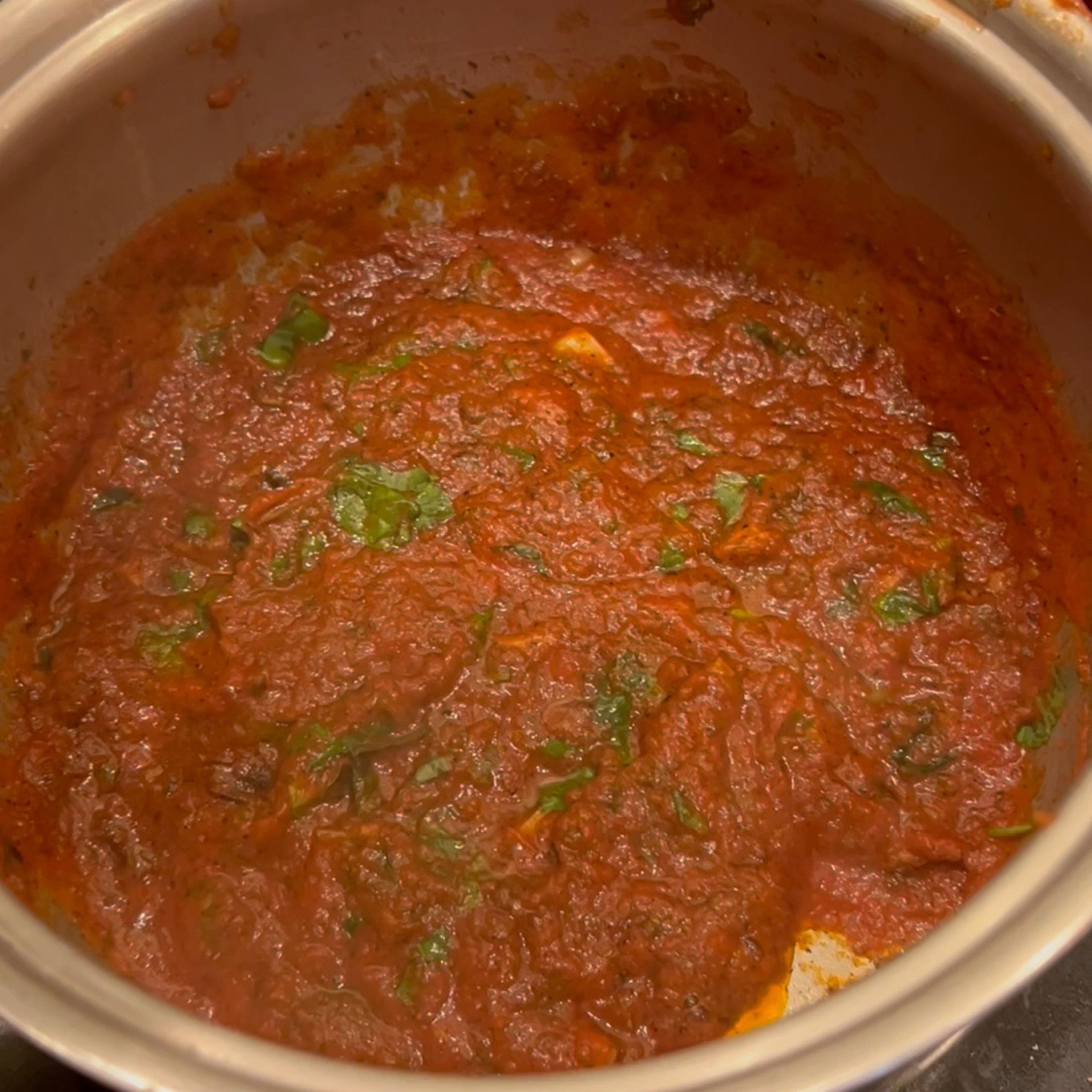 add tomato paste, water, and some of the basil leaves into the pan and mix to combine