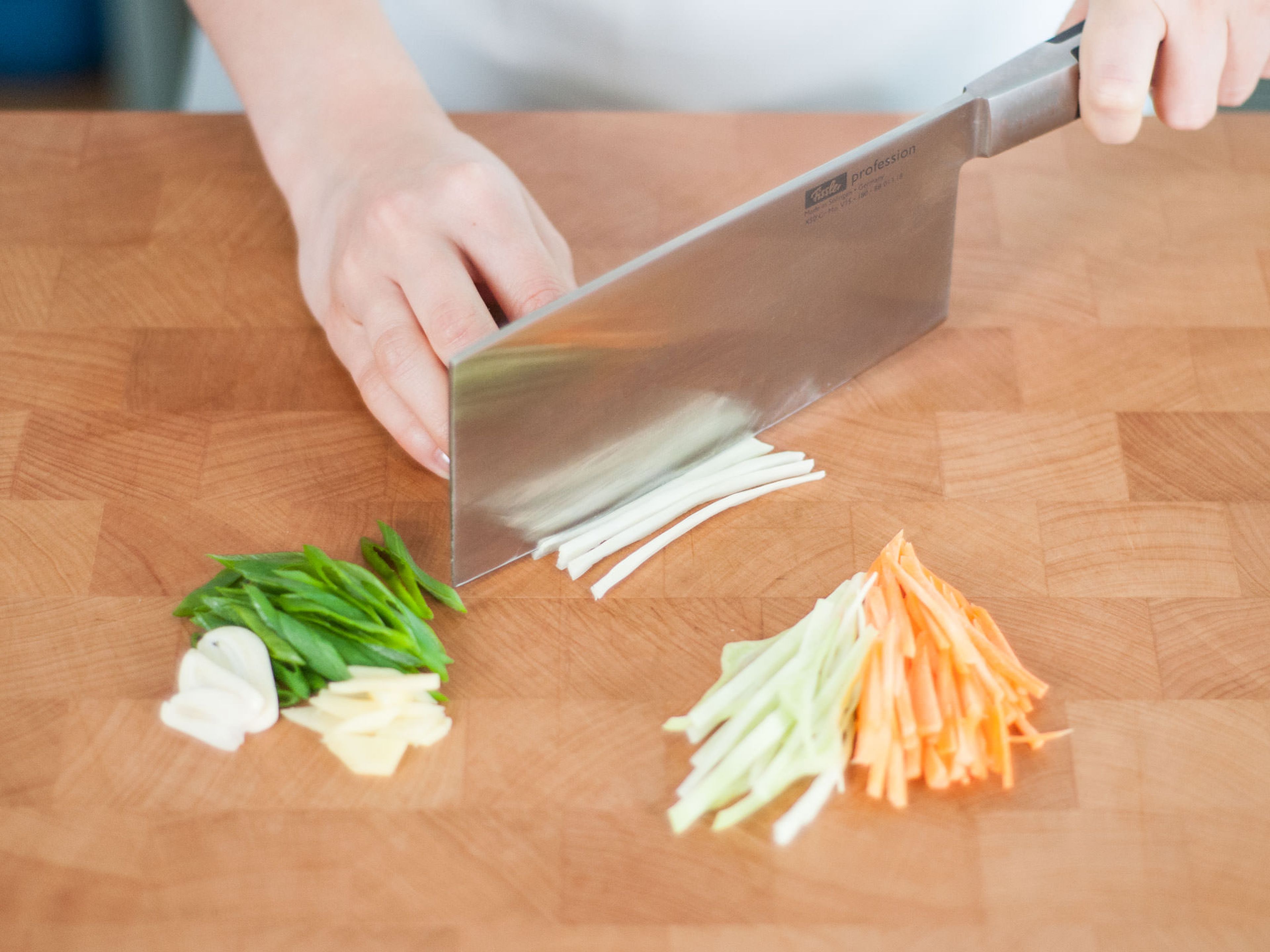 Peel and finely slice ginger and garlic. Peel carrots, then julienne them, along with green onions and white cabbage.