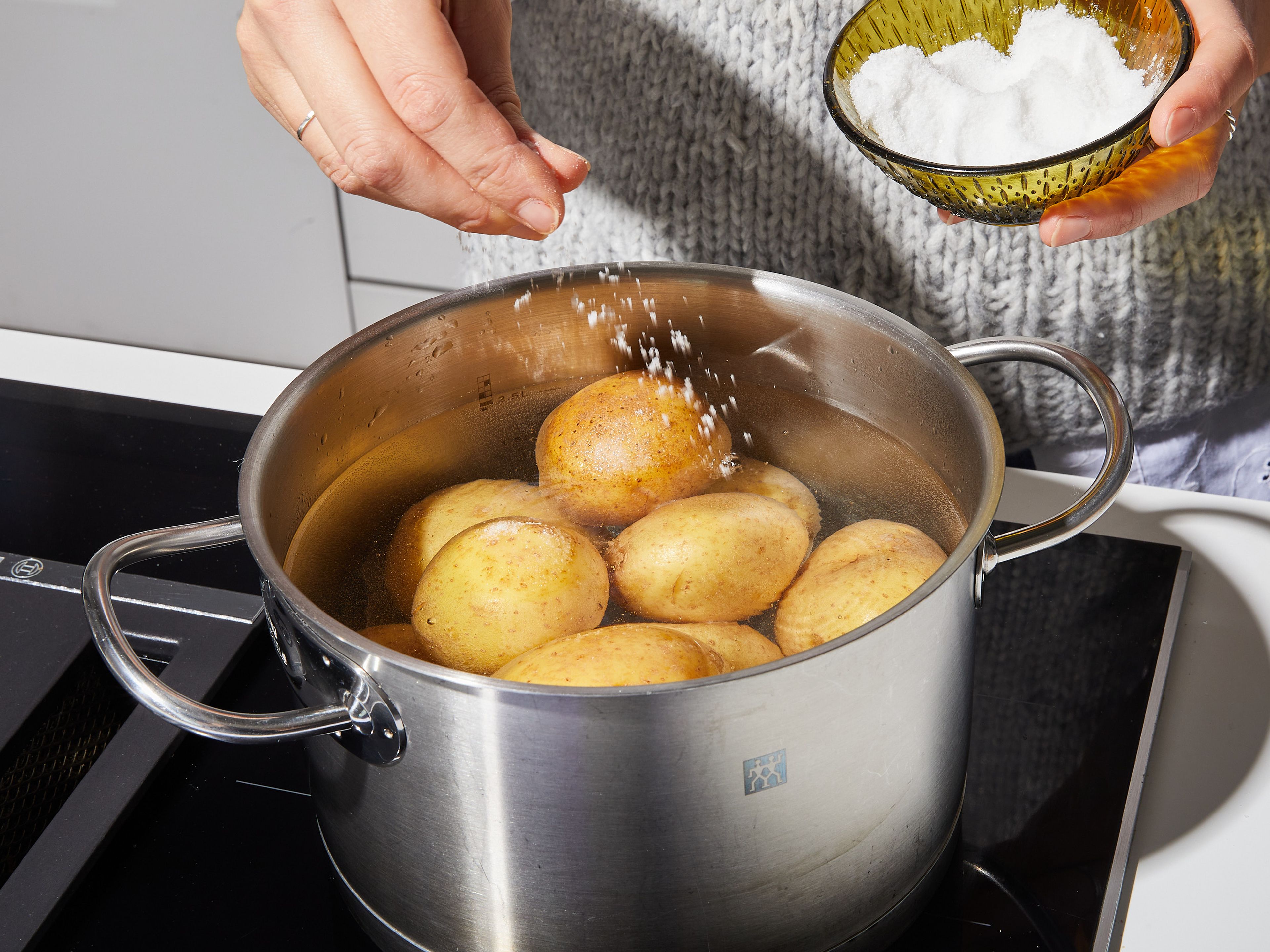 Den Ofen auf 200°C vorheizen. Kartoffeln waschen und dabei die Haut dran lassen. In einen großen Topf mit gesalzenem Wasser geben. Zum Kochen bringen, dann die Hitze leicht reduzieren und mit einem Deckel halb abgedeckt ca. 20 Min. kochen lassen, oder bis du sie leicht mit einer Gabel einstechen kannst. Kartoffeln abgießen und mit Abstand auf ein großes Backblech legen. Ca. 5 Min. ruhen lassen, um sie etwas ausdampfen zu lassen.