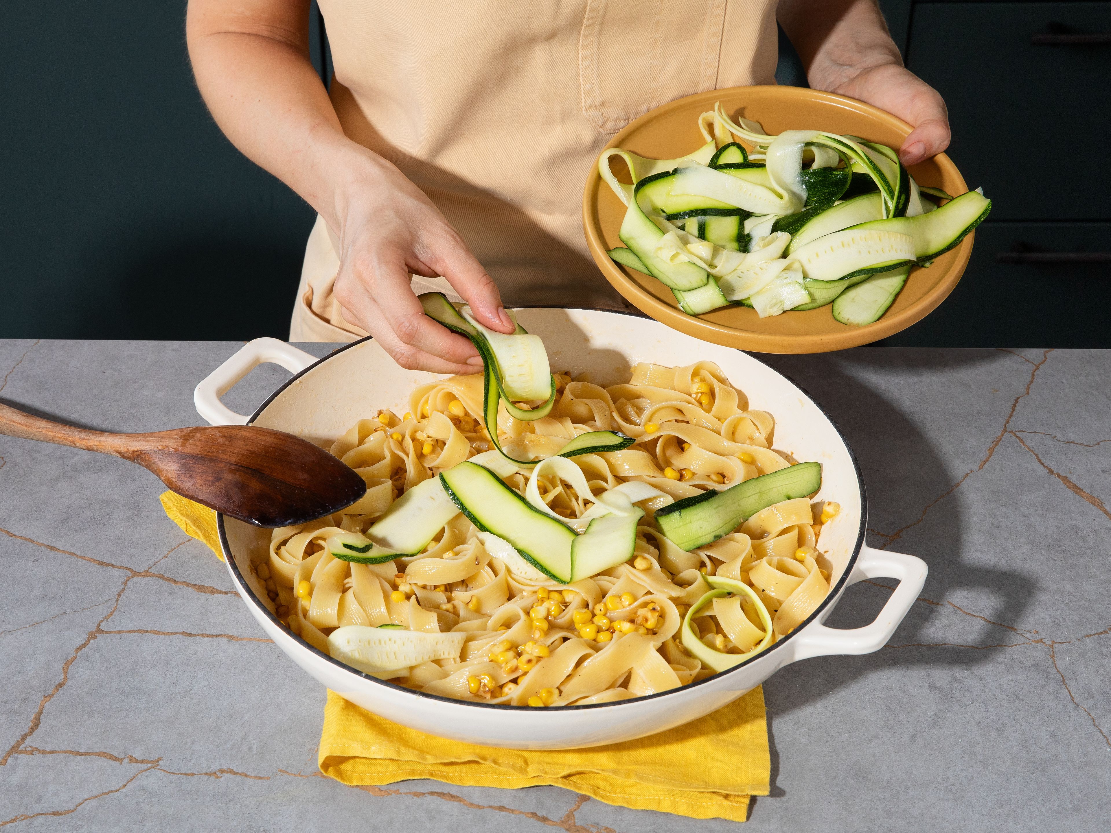Die Pappardelle zum Mais in die Pfanne geben und vom Herd nehmen. Die Eigelb-Parmesan-Mischung unterrühren und zu einer cremigen Soße emulgieren. Nach Bedarf mehr Pastawasser hinzufügen. Zucchinistreifen unterheben, kurz schwenken und sofort mit extra Parmesan und schwarzem Pfeffer servieren.