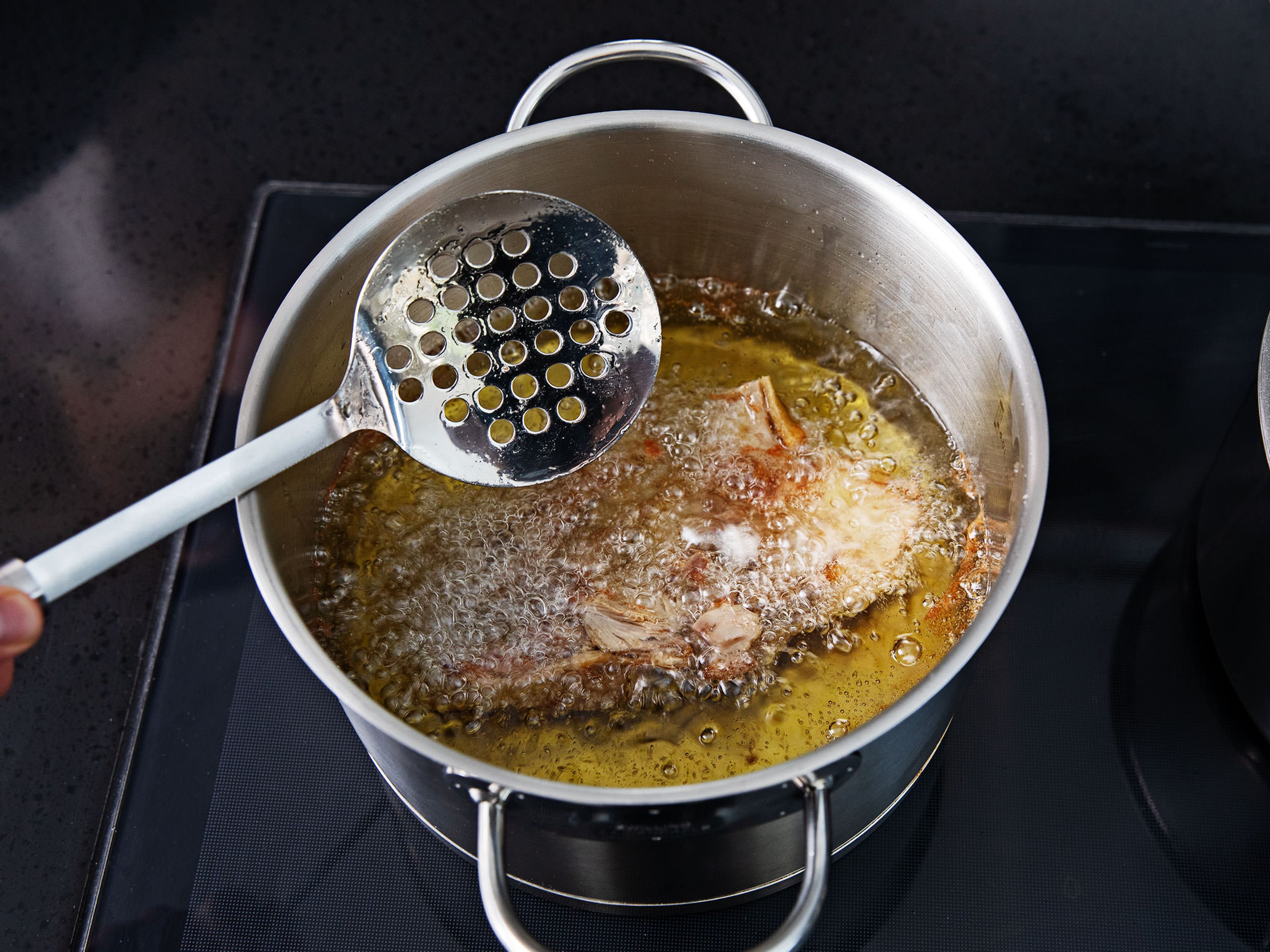 Die gegarte, leicht abgekühlte Ente in zwei Hälften schneiden und die Wirbelsäule entfernen. Die Brühe in einen sauberen Topf durch ein Sieb abgießen und über hoher Hitze kochen, bis sie zu einer Soße eindickt. Einen weiteren Topf mit Öl erhitzen und die Entenhälften darin anbraten, bis sie kross sind. Anschließend auf einem Teller mit Küchenpapier abtropfen lassen.