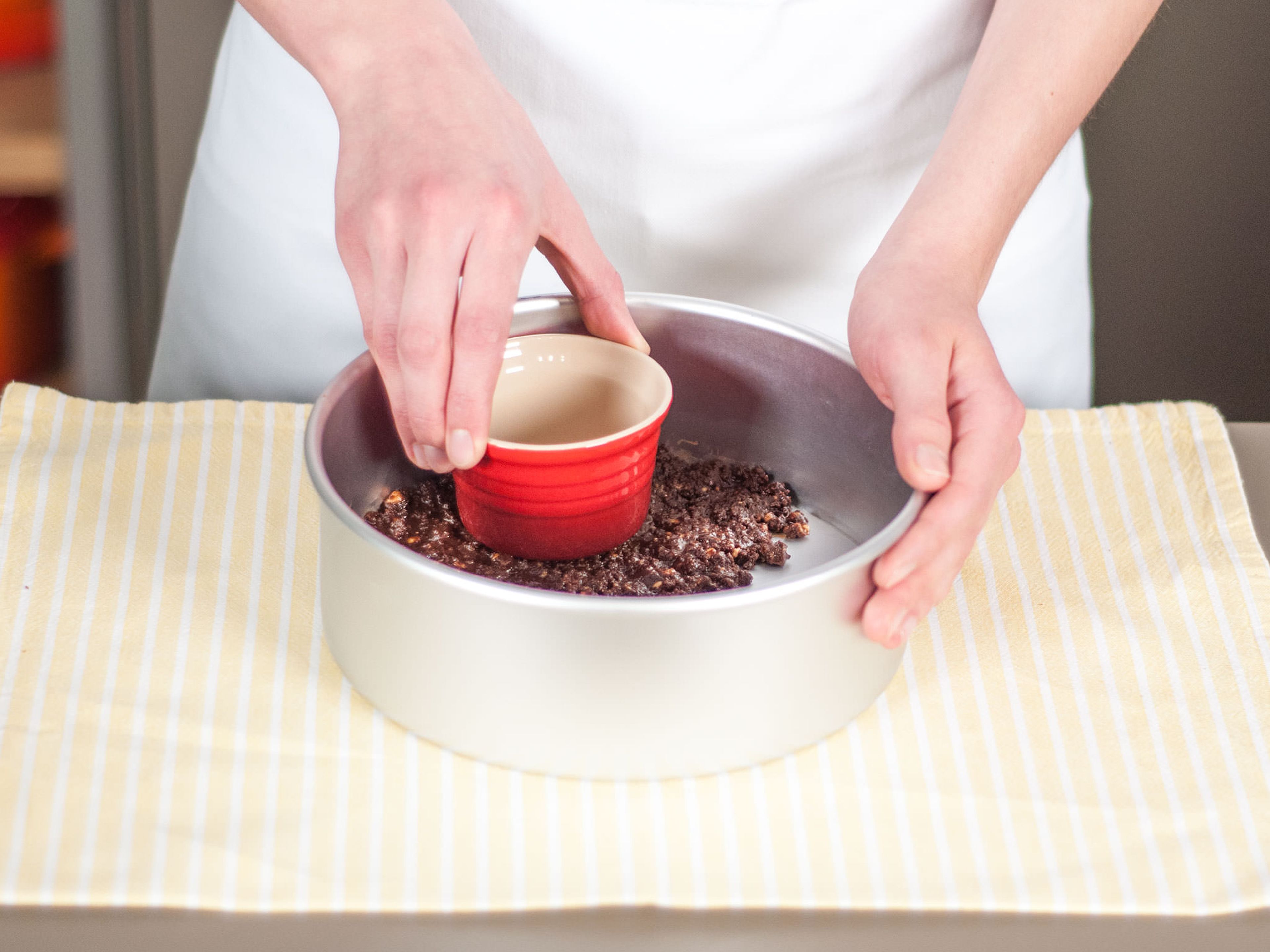 Kekskrümelmischung in eine runde Backform geben und sorgfältig an den Boden der Backform drücken.