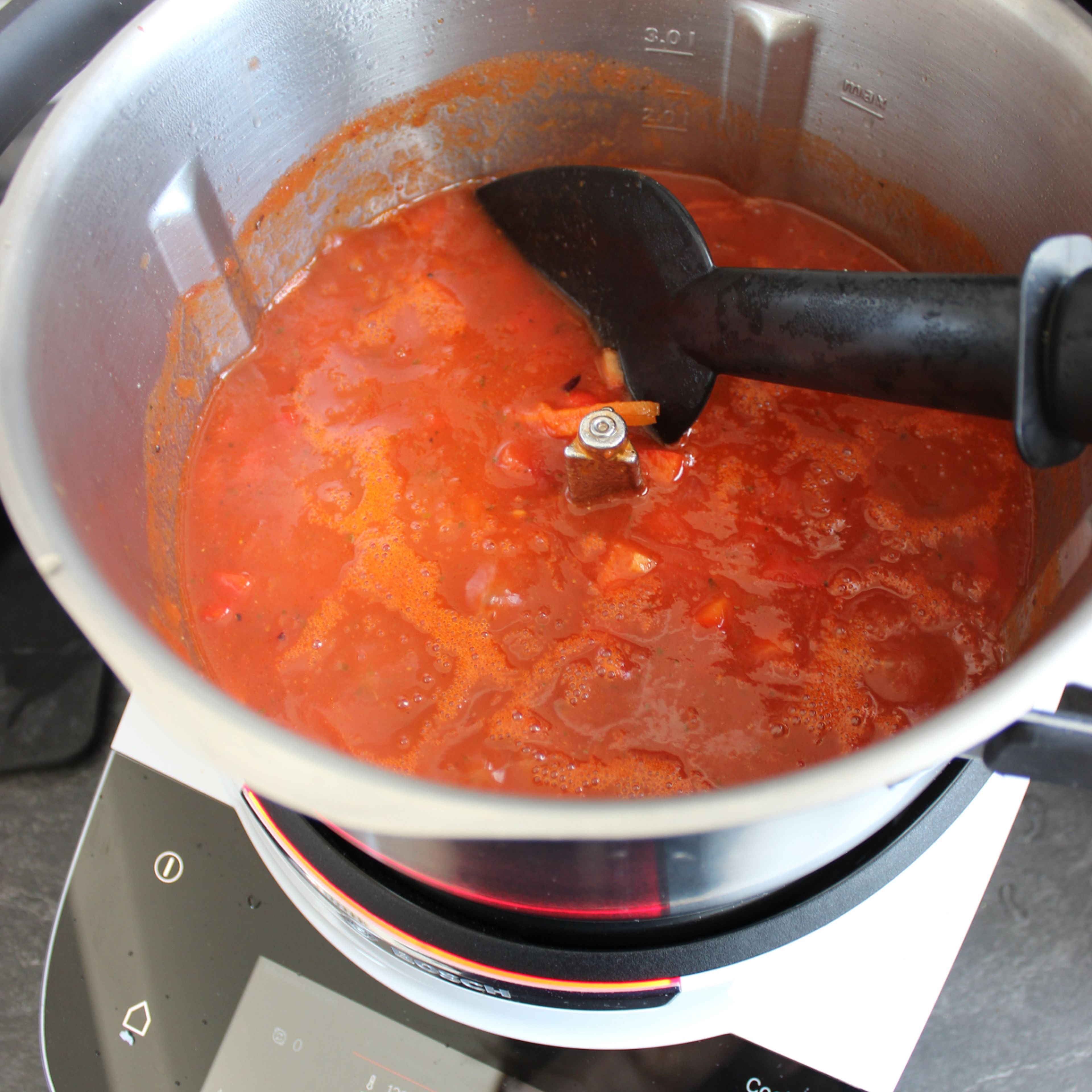 Den Cookit 3D-Rührer einsetzen. Manuelles Kochen auswählen und die rote Zwiebel bei geschlossenem Deckel, ohne Messbecher, anbraten (3D-Rührer | Stufe 3 | 140°C | 2 Min.). Karotte und Paprika hinzugeben und weiter bei geschlossenem Deckel, ohne Messbecher, anbraten (3D-Rührer | Stufe 3 | 140°C | 2 Min.). Dann die Tomaten aus der Dose und eine Tasse Wasser hinzugeben und den Deckel schließen. Die Hitze auf 100°C reduzieren und köcheln lassen (3D-Rührer | Stufe 3 | 100°C | ).