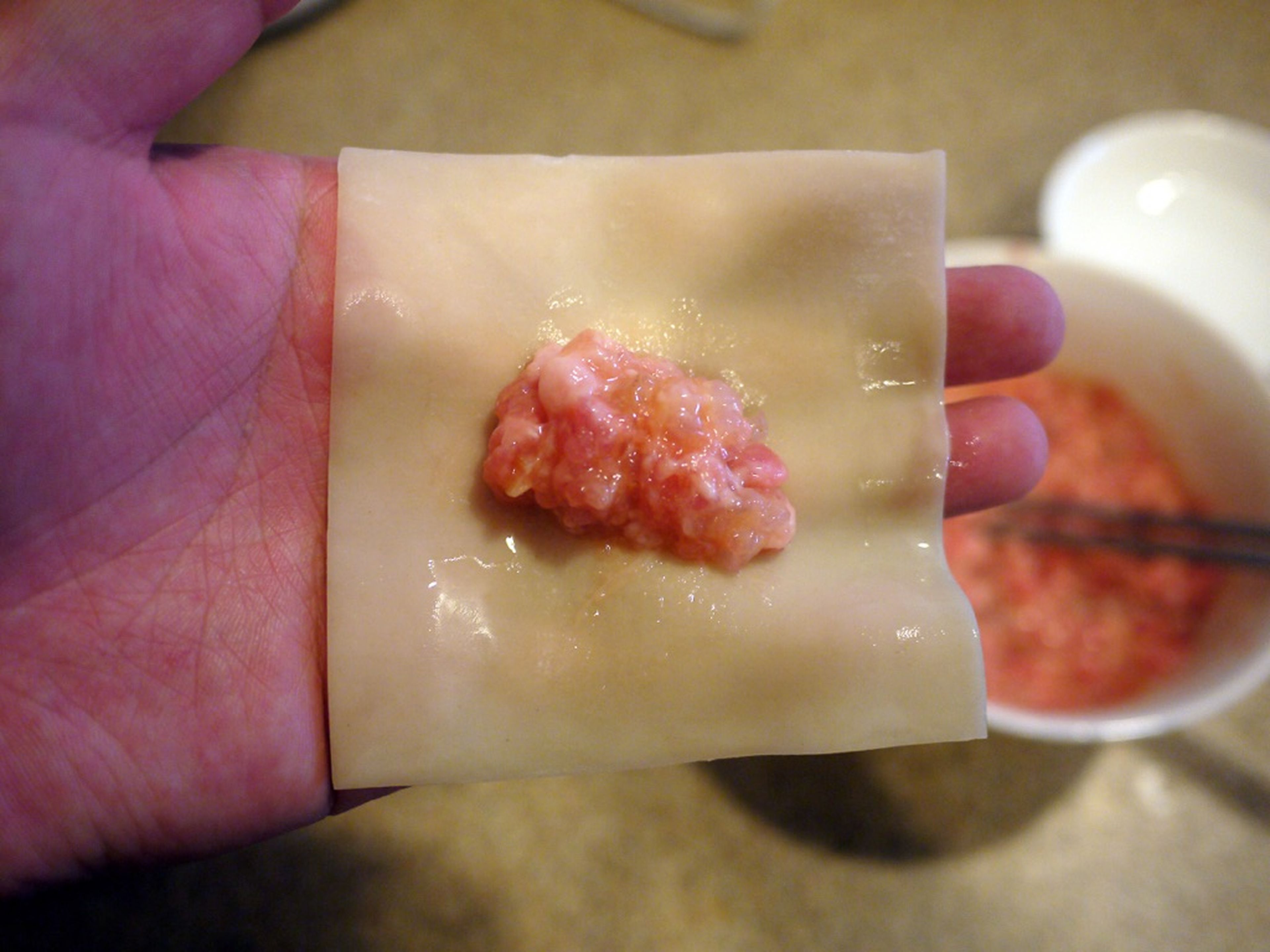 Put a dumpling wrapper on your dry hand. Add 1 teaspoon of the stuffing in the center. Wet the left, right and bottom sides of the wrapper with some water.