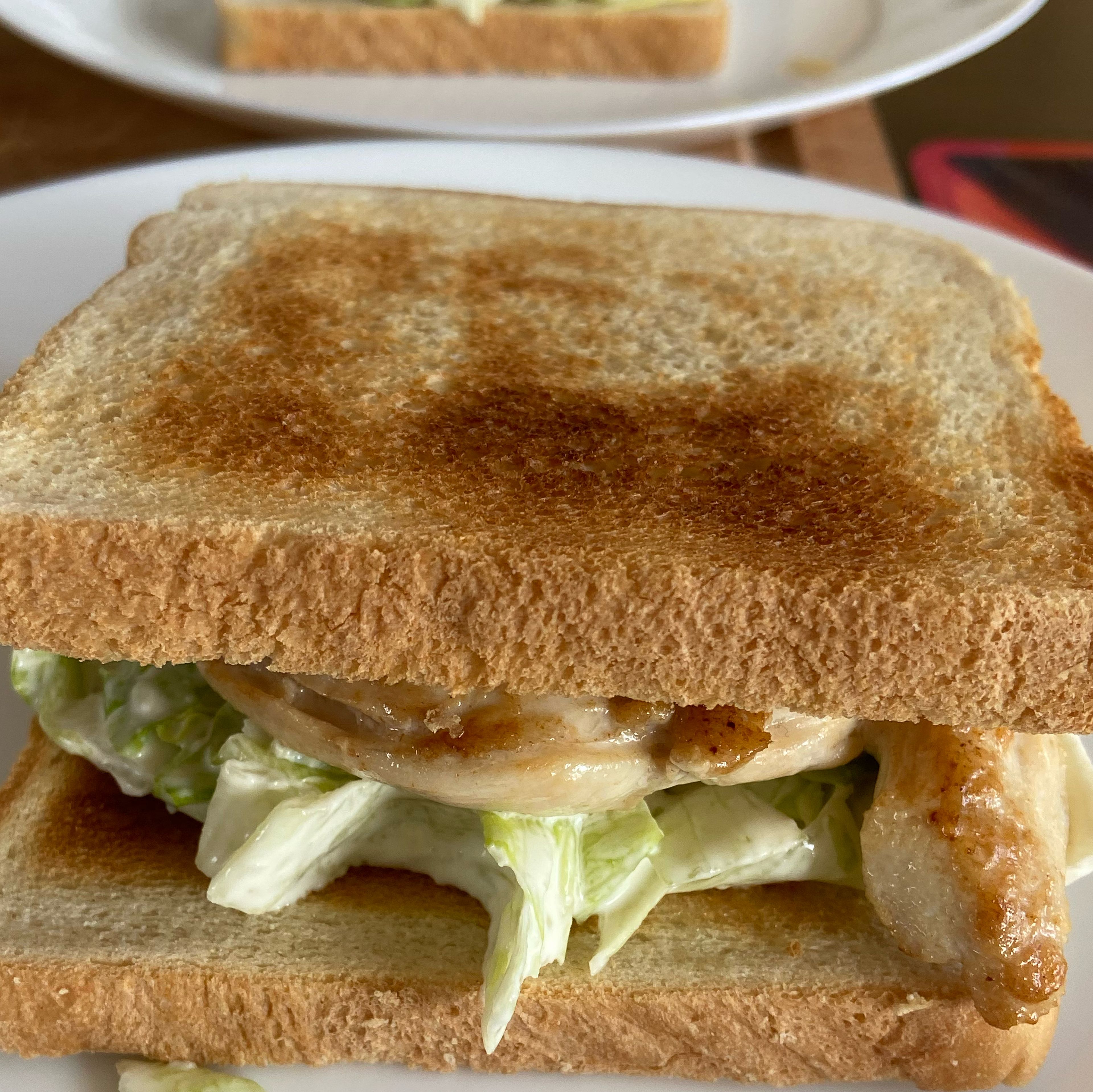 Lay the first bread slice and add a generous portion of the lettuce with the sauce, add the chicken breast on top, 2 bacon strips on the chicken and another slice of bread.
