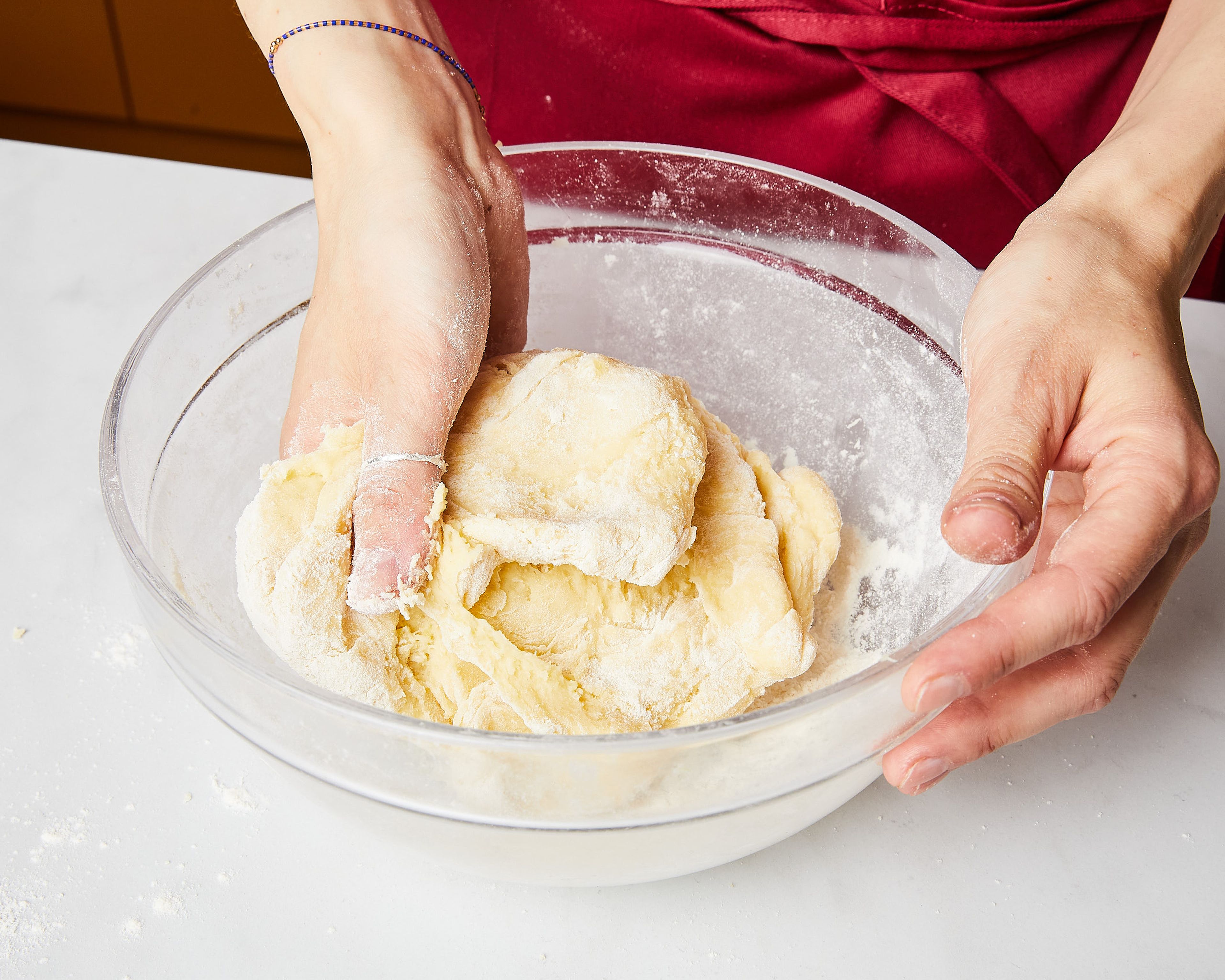 Heiße Kartoffeln abgießen und in einem Sieb kurz ausdampfen lassen. Durch eine Kartoffelpresse in eine große Schüssel drücken oder sie mit einem Kartoffelstampfer darin fein zerstampfen. Die Hälfte der Butter in kleinen Stücken, sowie Eigelbe hinzugeben und mit einem Löffel oder dem Kartoffelstampfer gut vermengen. Salz und esslöffelweise das Mehl hinzufügen und mit den Händen gut verkneten, bis der Teig nicht mehr zu stark klebt. Eventuell etwas mehr Mehl hinzufügen. Teig ca. 5–10 Min. abkühlen lassen.