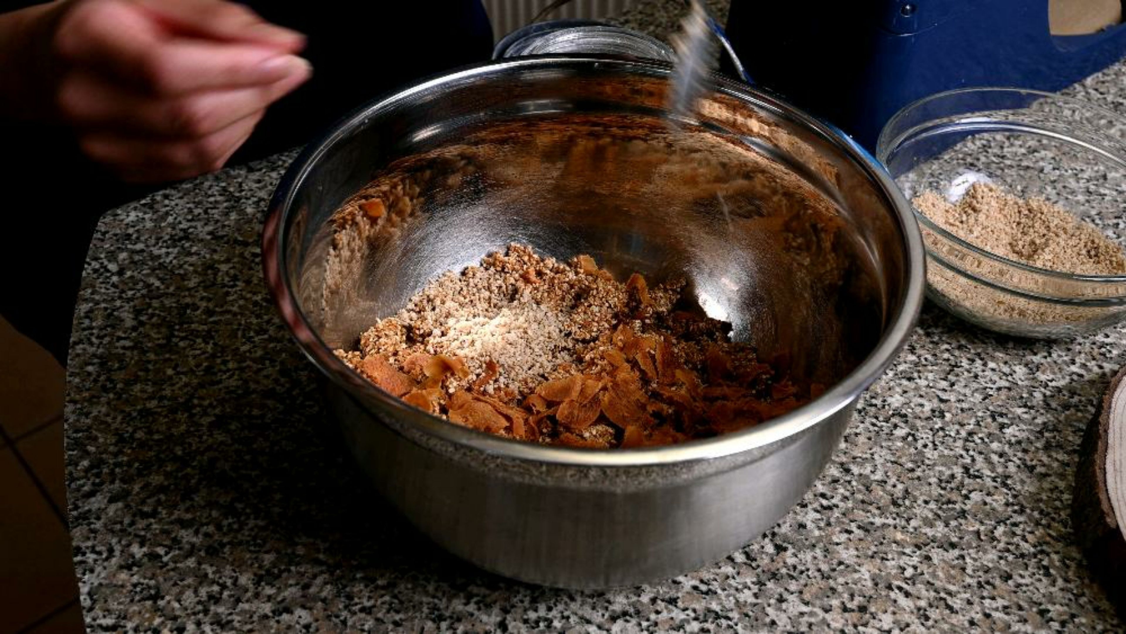 Gradually add the fine sesame seed powder to the large bowl and mix to combine with the pulsed sesame seeds and jaggery.