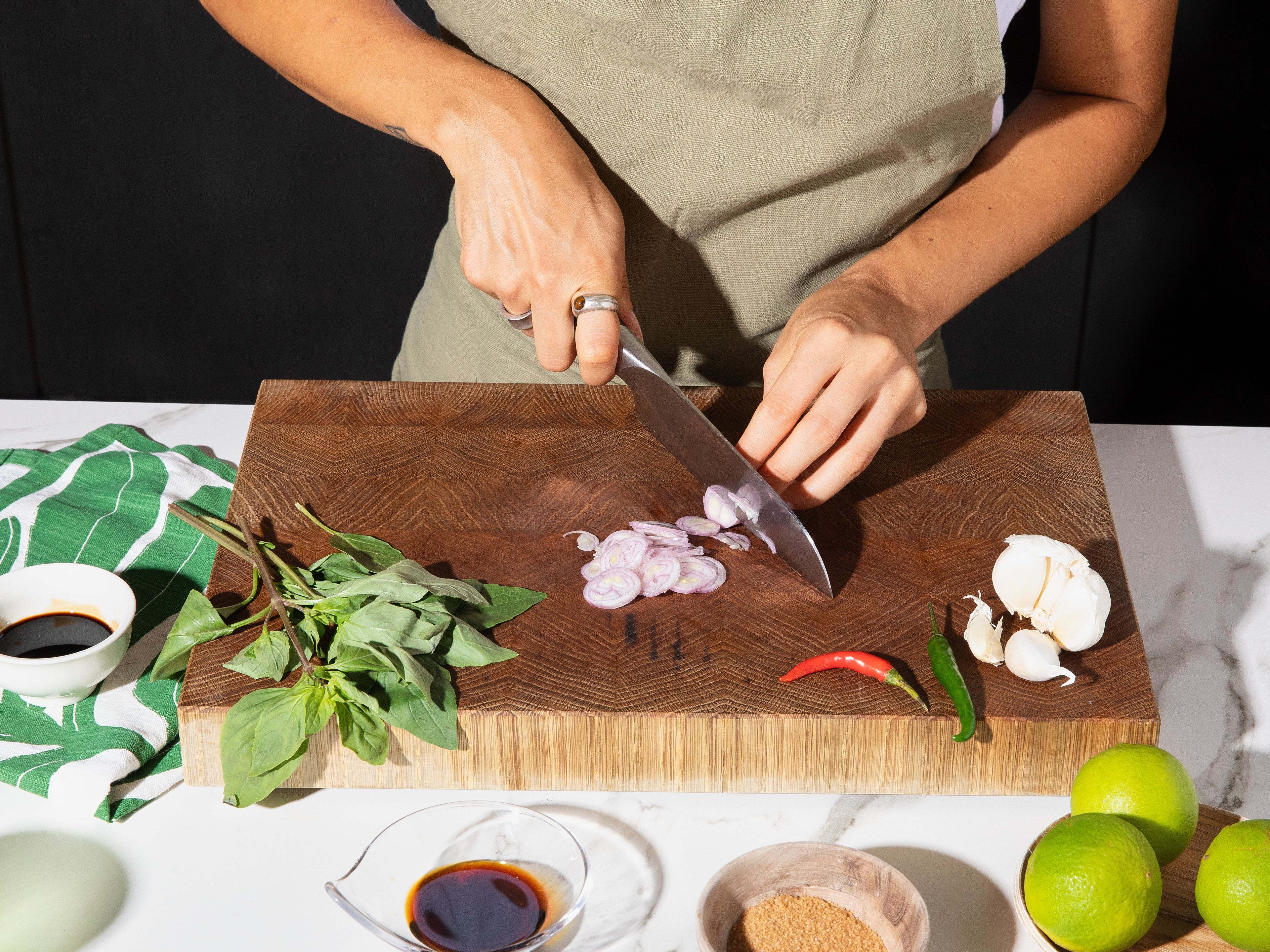 Finely chop garlic and chilies. Cut shallots into thin rings. Pick basil leaves from the stems. In a small bowl, whisk together light and dark soy sauce, oyster sauce, fish sauce, and sugar. Blanch gnocchi in boiling water for approx. 2 min., then drain, reserving some of the cooking water.