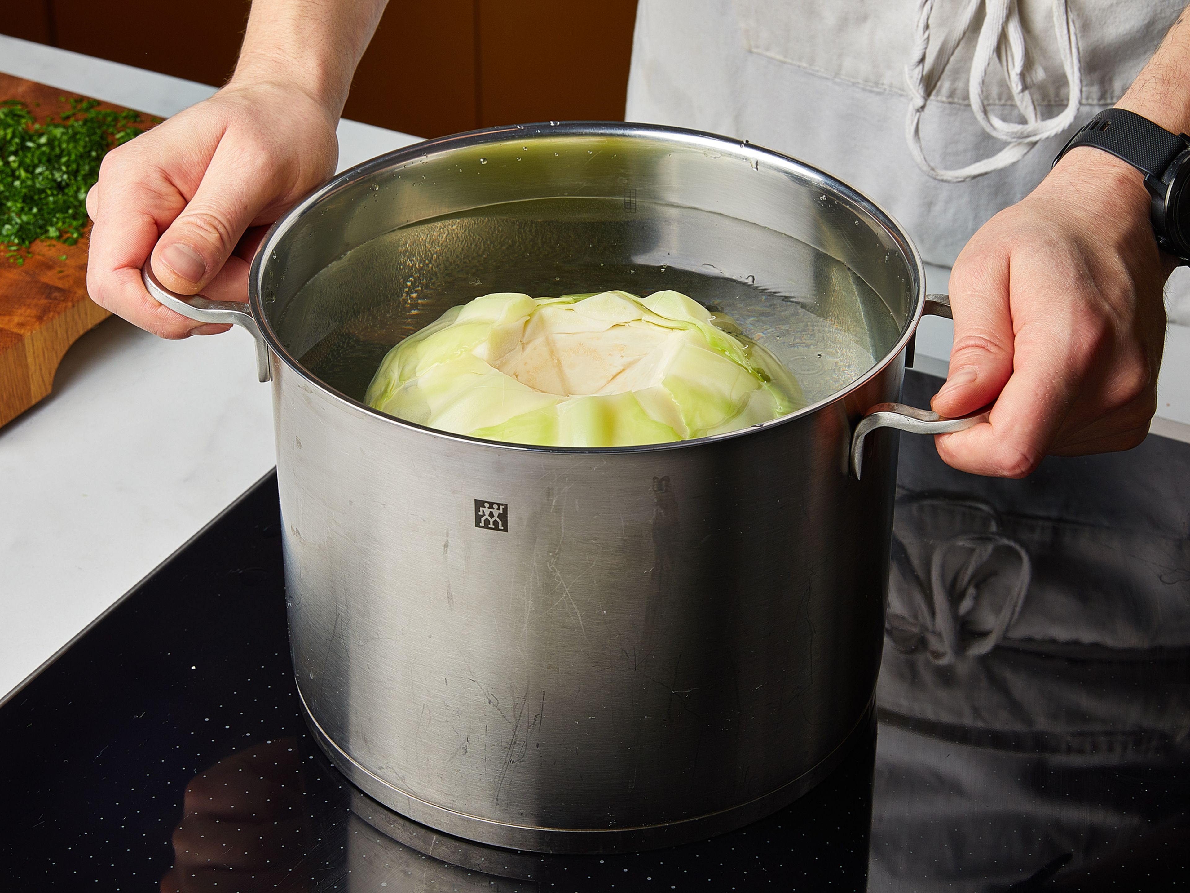 In einem großen Topf Wasser mit Salz zum Kochen bringen. Den Strunk vom Kohlkopf entfernen. Kohlkopf ca. 10 Min. blanchieren, bis die äußeren Blätter weich sind und sich leicht ablösen lassen. Aus dem Wasser nehmen, kurz abkühlen lassen und genügend Kohlblätter für die Menge der Rouladen abziehen. Petersilie fein hacken. Brötchen in Würfel schneiden. Champignons grob hacken. Zwiebeln schälen und fein würfeln. Knoblauch schälen und fein hacken. Das Wasser aus dem Topf entfernen und den Topf trocken wischen. Den Topf wieder auf mittlere Hitze stellen und etwas Pflanzenöl erhitzen. Champignons und die Hälfte der Zwiebelwürfel zugeben und ca. 3–4 Min. glasig dünsten. Mit Pflanzenmilch ablöschen und großzügig mit gemahlenem Muskat, Senf, Salz und Pfeffer würzen.