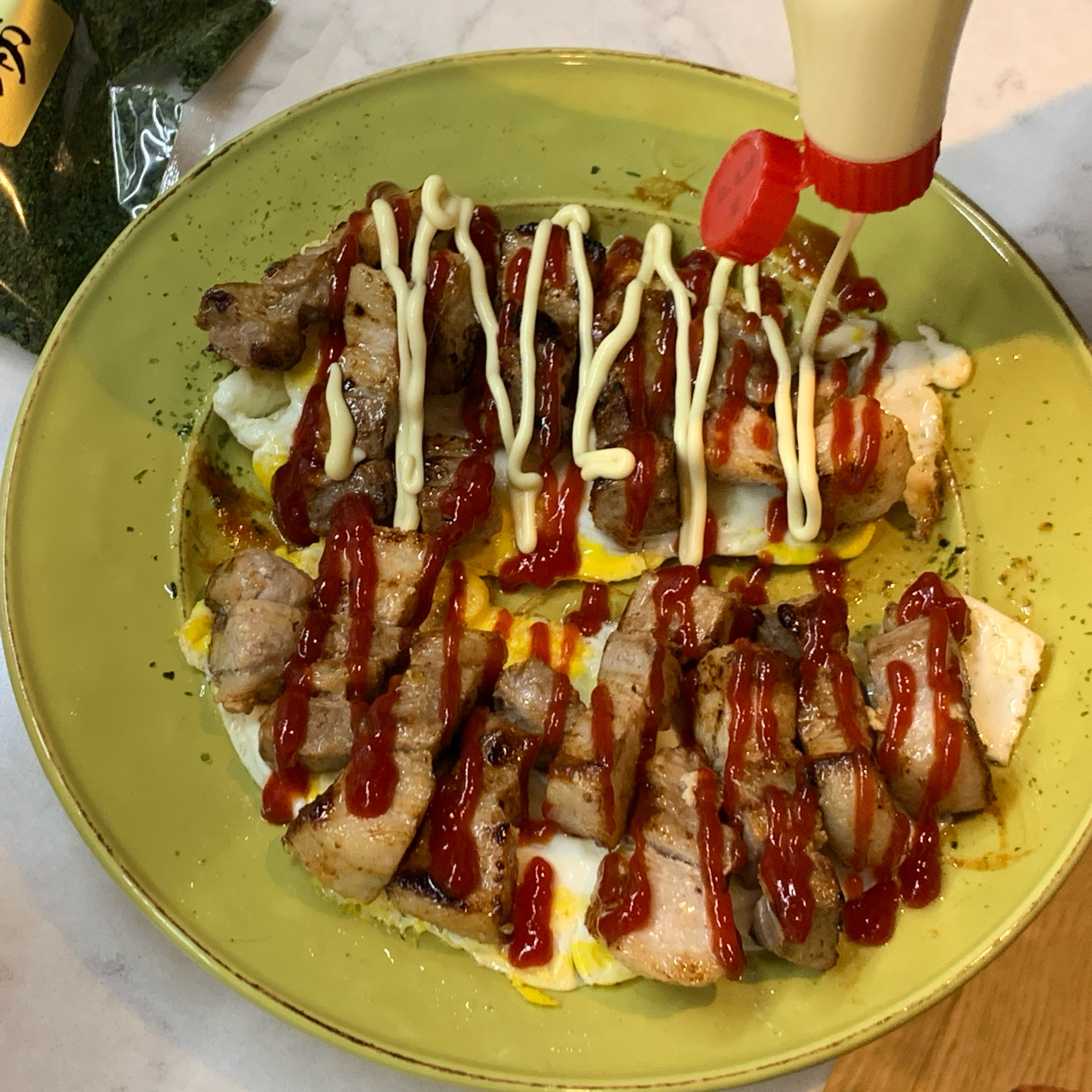 Place the fried eggs at the bottom and then the pork belly. Squeeze the ketchup, mayonnaise and okonomiyaki sauce at your choice. Sprinkle the nori and place a small amount of bonito flake at the top.