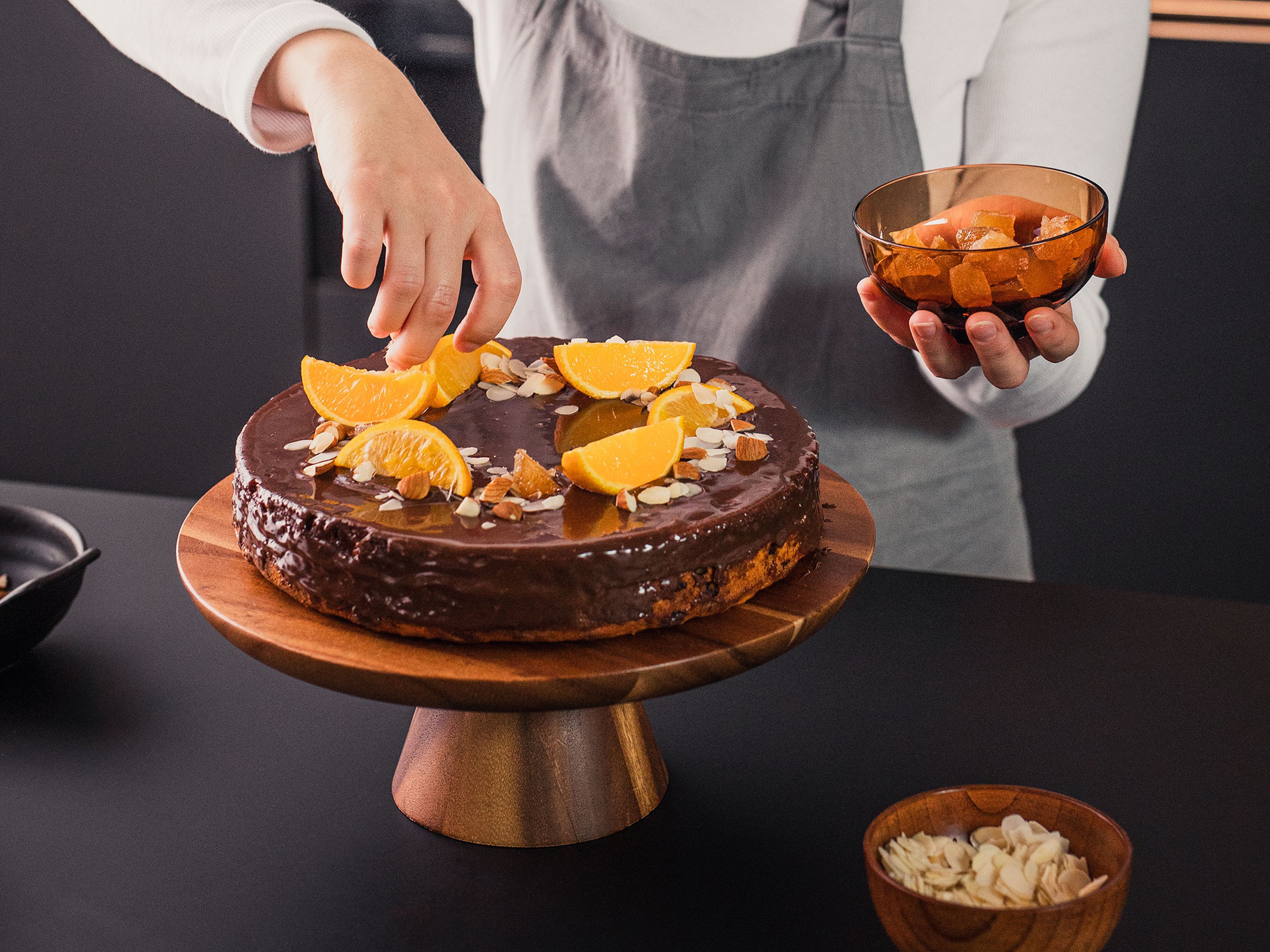 Spread some of the chocolate glaze on top, then add the other half of the cake. Cover with remaining chocolate glaze. Let chill for approx. 20 min. Slice the second orange and garnish cake with orange slices, sliced and chopped almonds, and candied ginger. Enjoy!