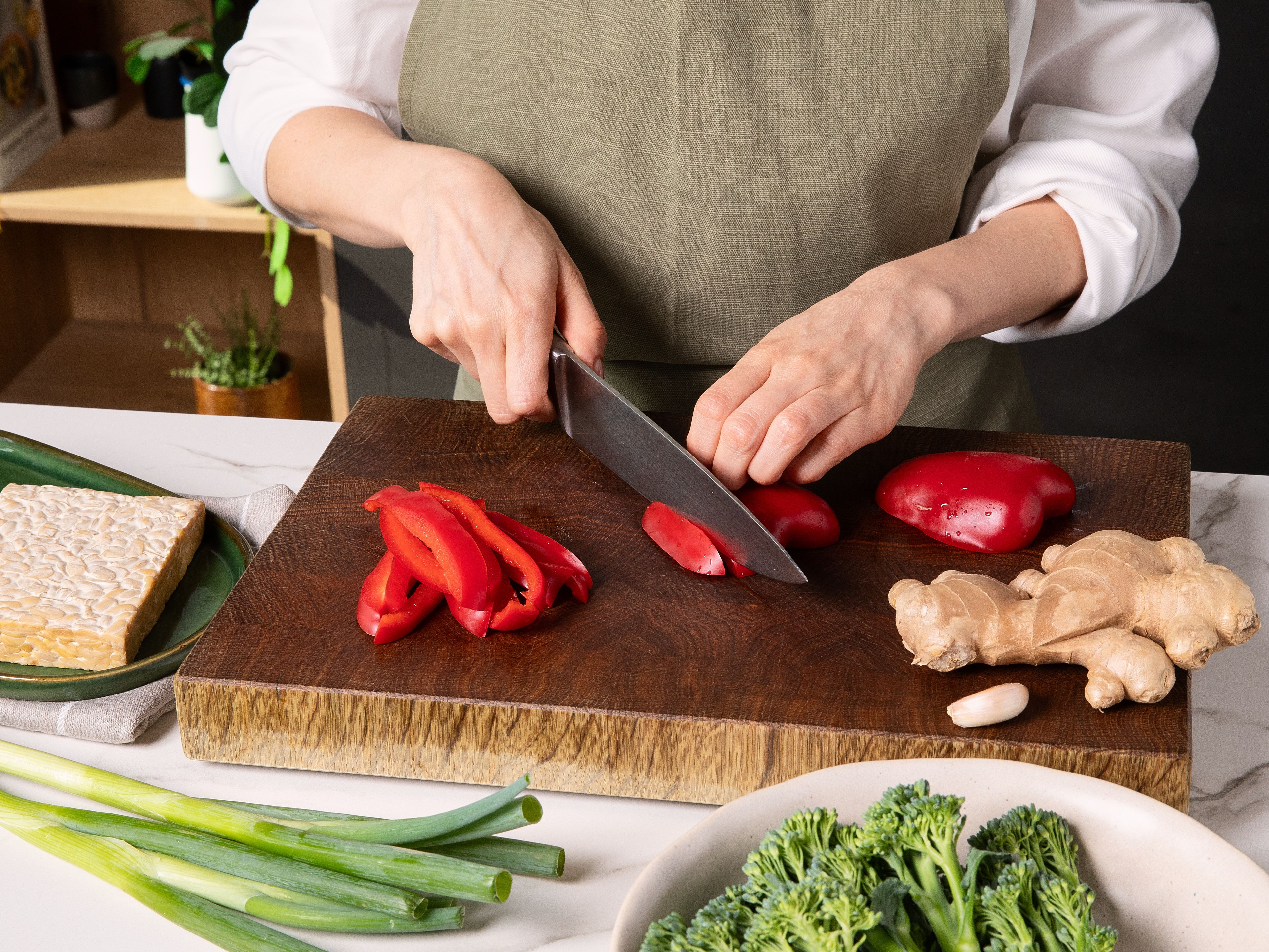 Brokkolini in mundgerechte Stücke teilen, Paprika in Streifen schneiden, Frühlingszwiebeln in feine Ringe schneiden, dabei Weiß und Grün trennen. Knoblauch und Ingwer fein hacken. Tempeh in mundgerechte Stücke schneiden. In eine Schüssel geben, mit der Hälfte der Speisestärke bestäuben und vorsichtig vermengen.mundgerechte Stücke schneiden. In eine Schüssel geben, mit der Hälfte der Speisestärke bestäuben und vorsichtig vermengen.