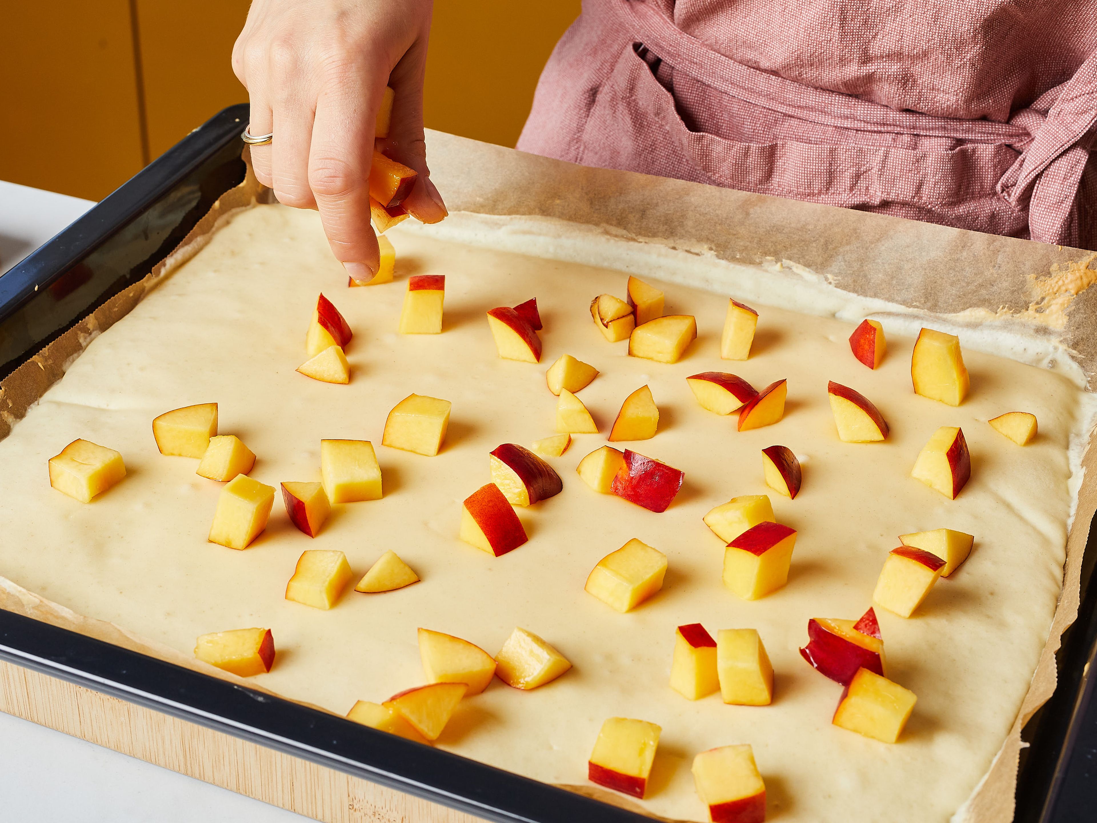 Spread the batter evenly with a spoon on a baking sheet lined with parchment paper. Bake the batter on the middle shelf for 5 minutes. Then remove from the oven, spread the nectarine cubes evenly on top, press in lightly, and bake for another 5 min.