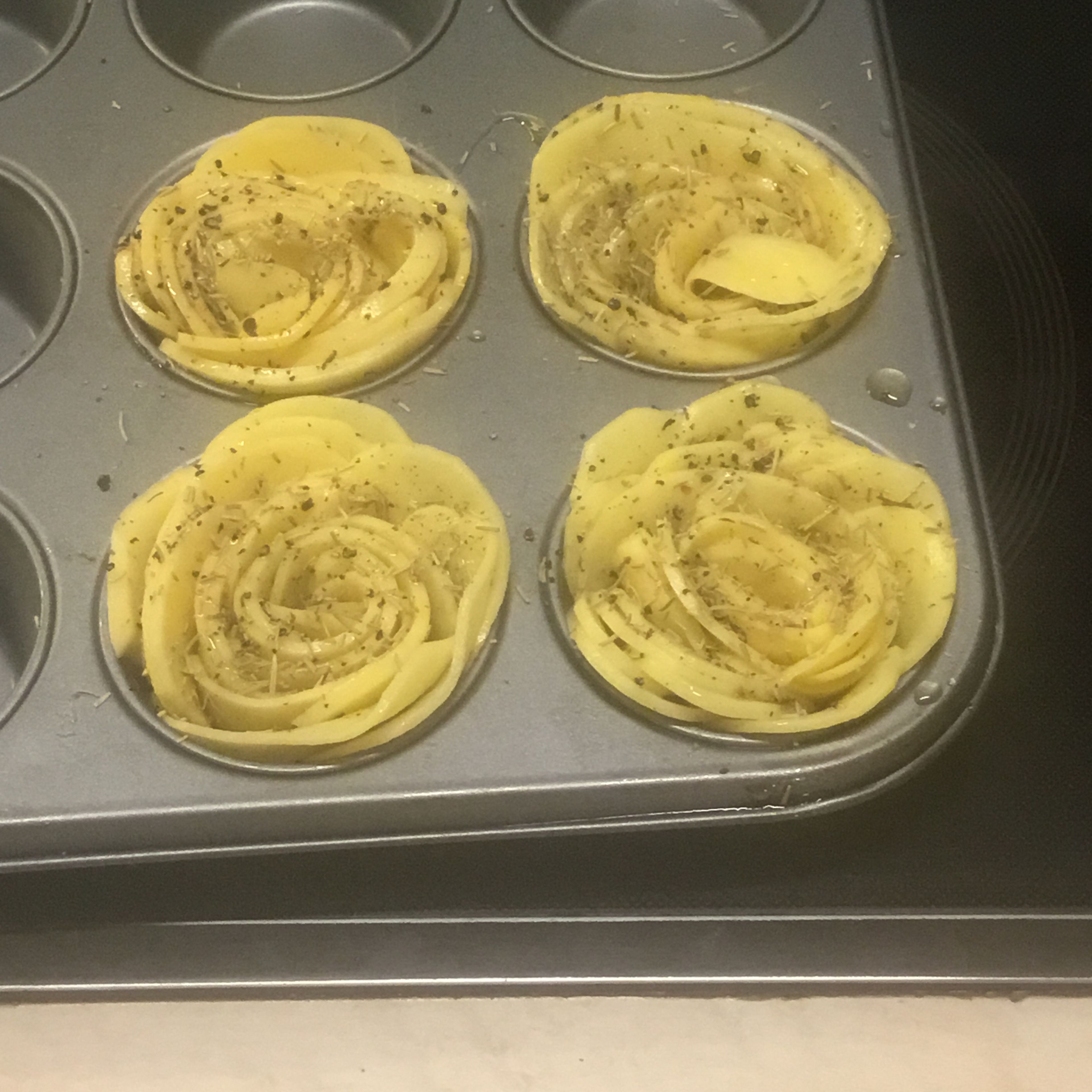 Die aufgerollten Kartoffelscheiben in ein Muffinblech stecken. Da sich die Röschen nicht immer so schön ins Muffinblech einfügen lassen mit kleinerer Rose beginnen und danach einzelne Kartoffelscheiben seitlich ins Muffinblech dazustecken.