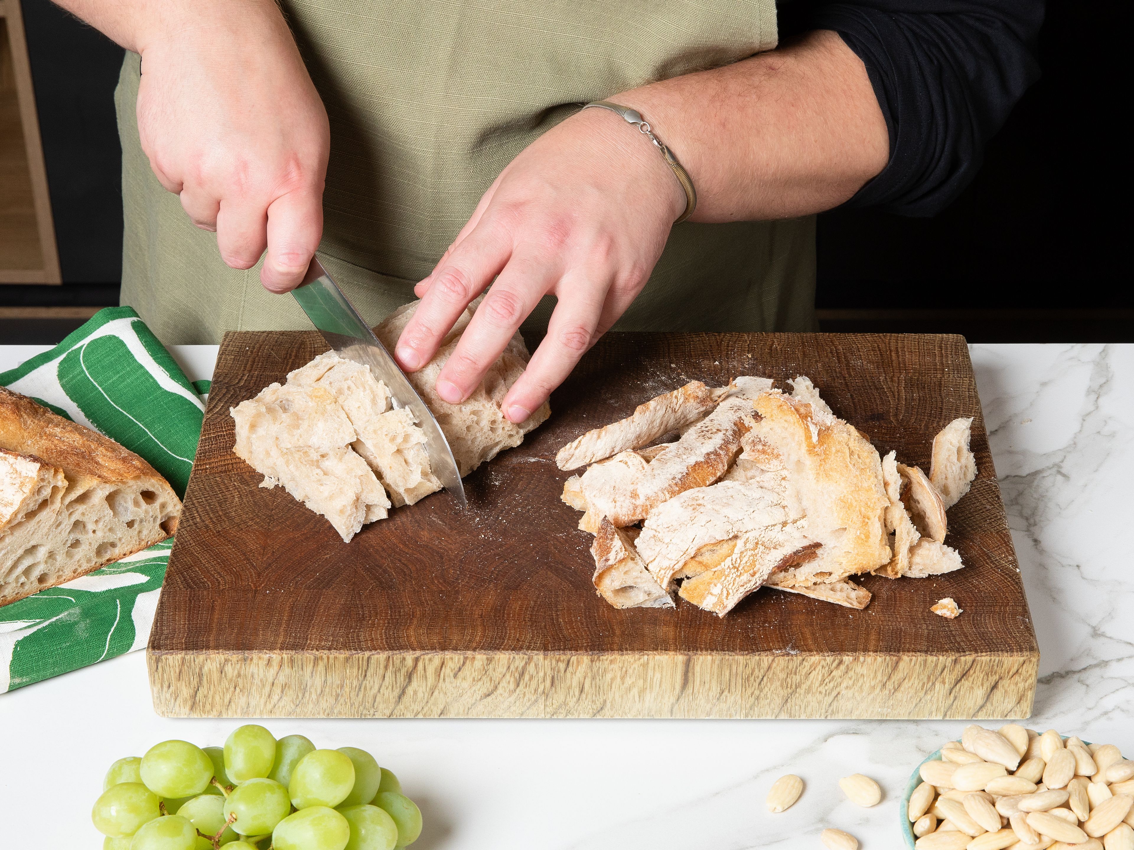 Die Kruste vom Weißbrot abschneiden, das Innere in Stücke schneiden und in etwas kaltem Wasser einweichen. Sobald es weich ist, gut ausdrücken. Den Knoblauch schälen und den inneren Strunk entfernen.