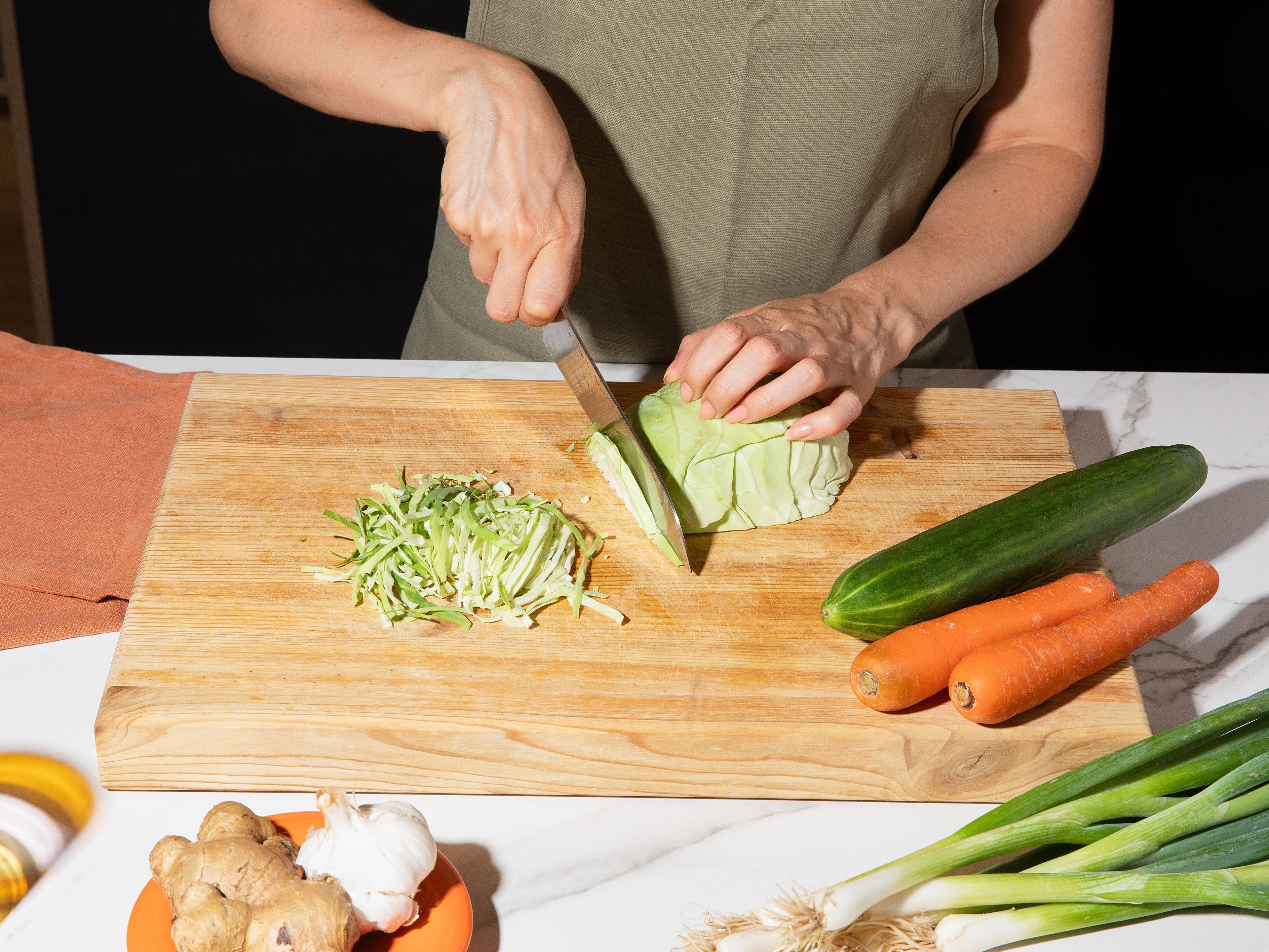 Slice or shred pointed cabbage and cucumber into fine strips. Peel carrots and also slice or shred into fine strips. Slice spring onions diagonally into fine rings and keep a few green rings for serving. Add everything to a large salad bowl.