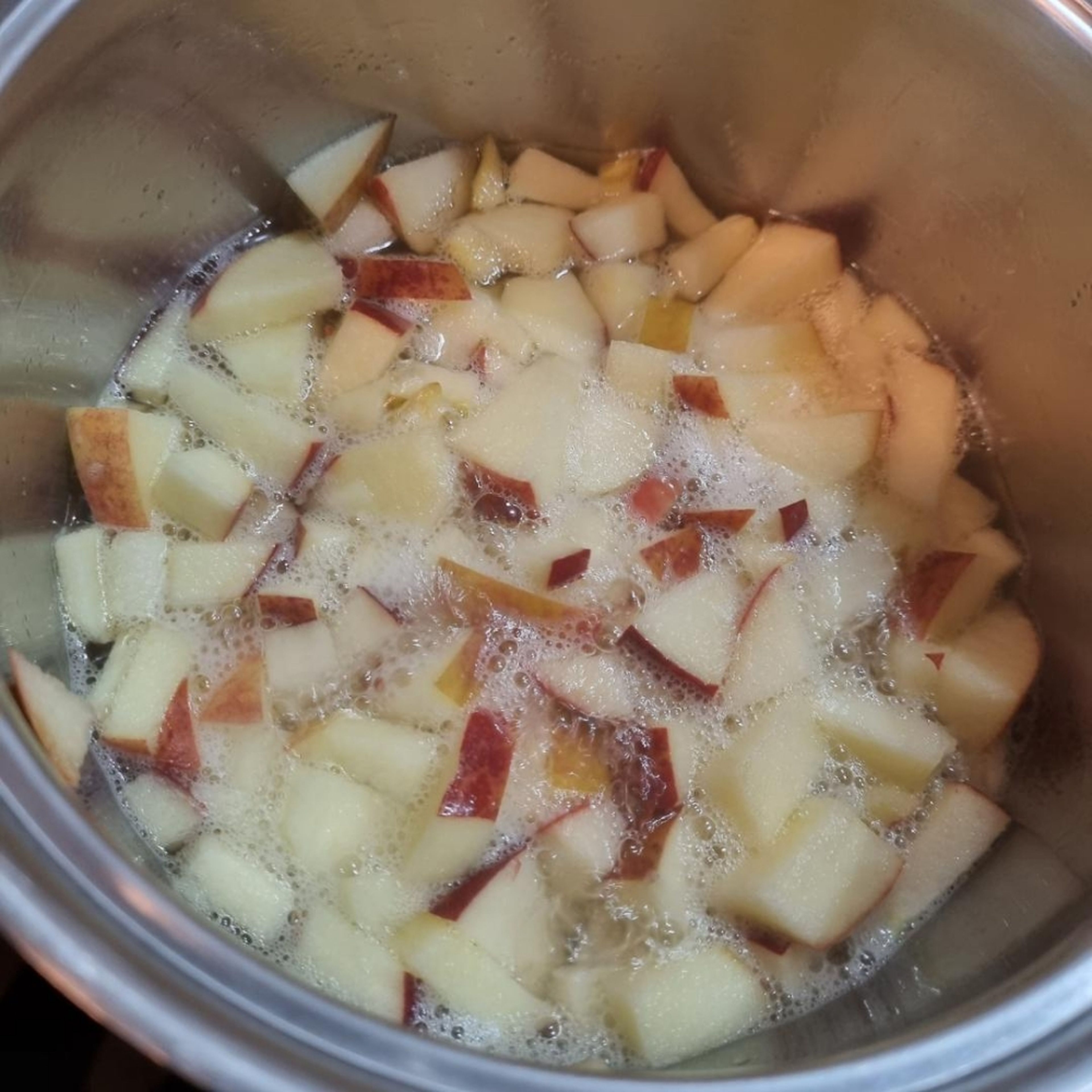 Den geschnittenen Apfel in ein Kochtopf geben, Zucker, Zitronensaft und ein bisschen von dem Wasser dazugeben. Das alles kurz zusammen aufkochen lassen.
