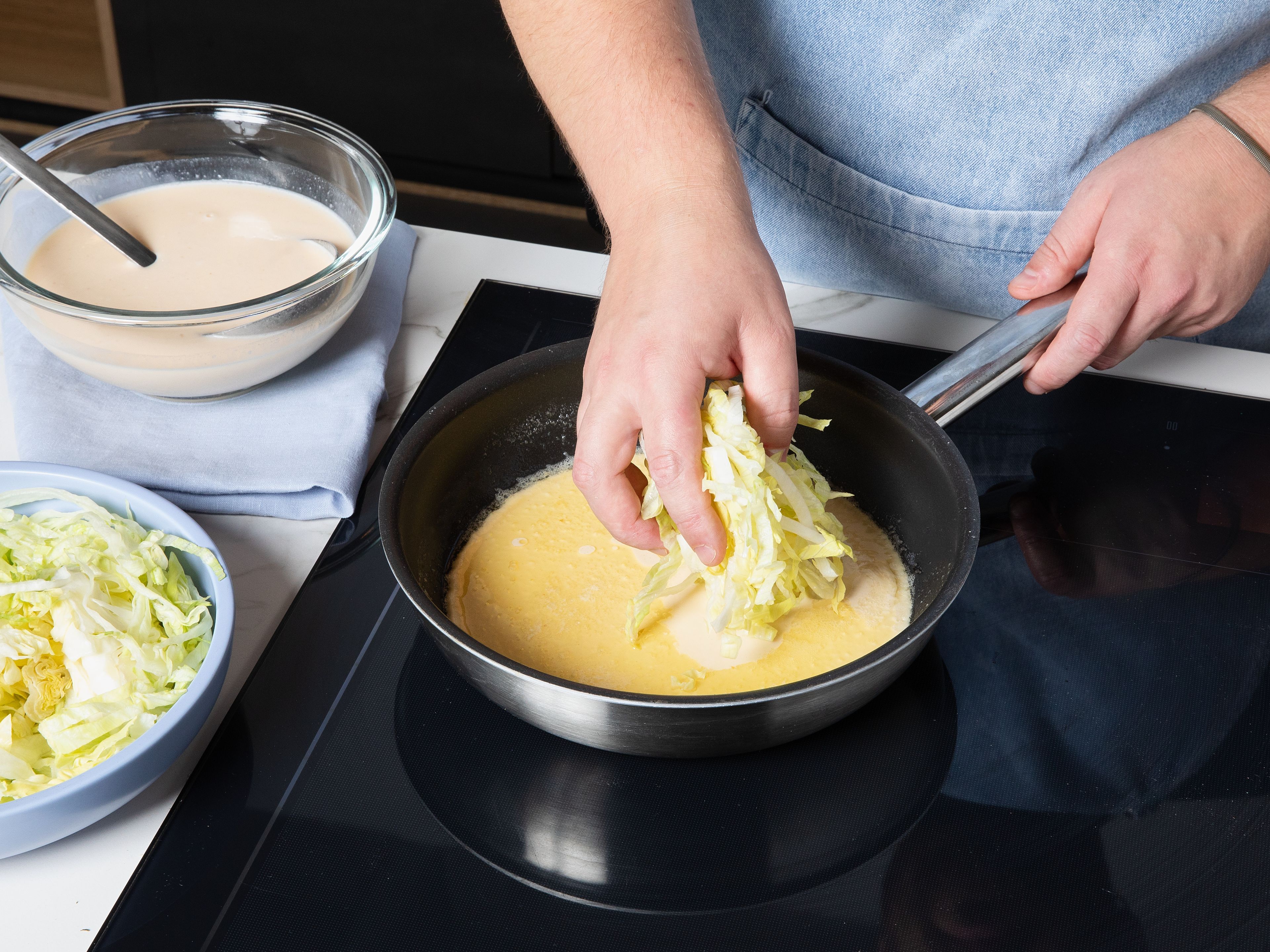 Eier, Milch, Zucker, Mehl, Salz und Mineralwasser in einer Schüssel  zu einem glatten Teig verrühren. Butter in einer Pfanne bei mittlerer bis hoher Hitze schmelzen. Etwas Pfannkuchenteig in die Pfanne geben, sodass der Boden dünn bedeckt ist. Eine Handvoll Salat darauf verteilen und sofort mit einer weiteren Schicht Pfannkuchenteig bedecken. Wenn der Boden fest ist, wenden und goldbraun backen. Wiederholen, bis kein Teig mehr übrig ist.