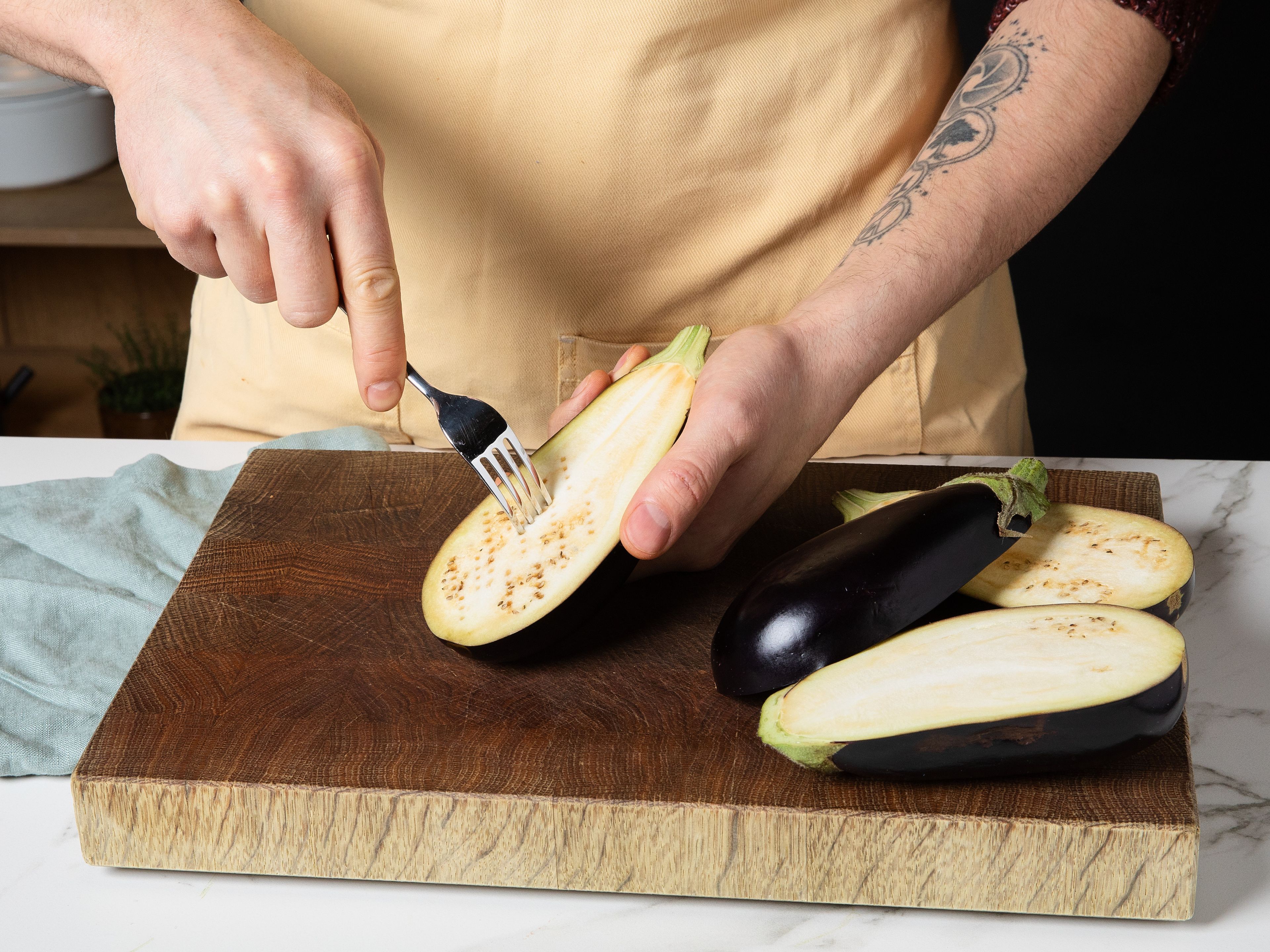Soak the walnuts in water the day before. On the day of preparation, preheat the oven to 200°C/ 390°F. To prepare eggplants, cut them in half lengthwise, prick the cut surfaces several times with a fork and place them cut-side up on a baking tray. Drizzle with oil and bake in the oven for approx. 40–50 min. until they are soft. Meanwhile, prepare the vegetables: peel and finely dice the carrots and onion. Wash the celery and cut into small pieces. Peel and finely chop the garlic.