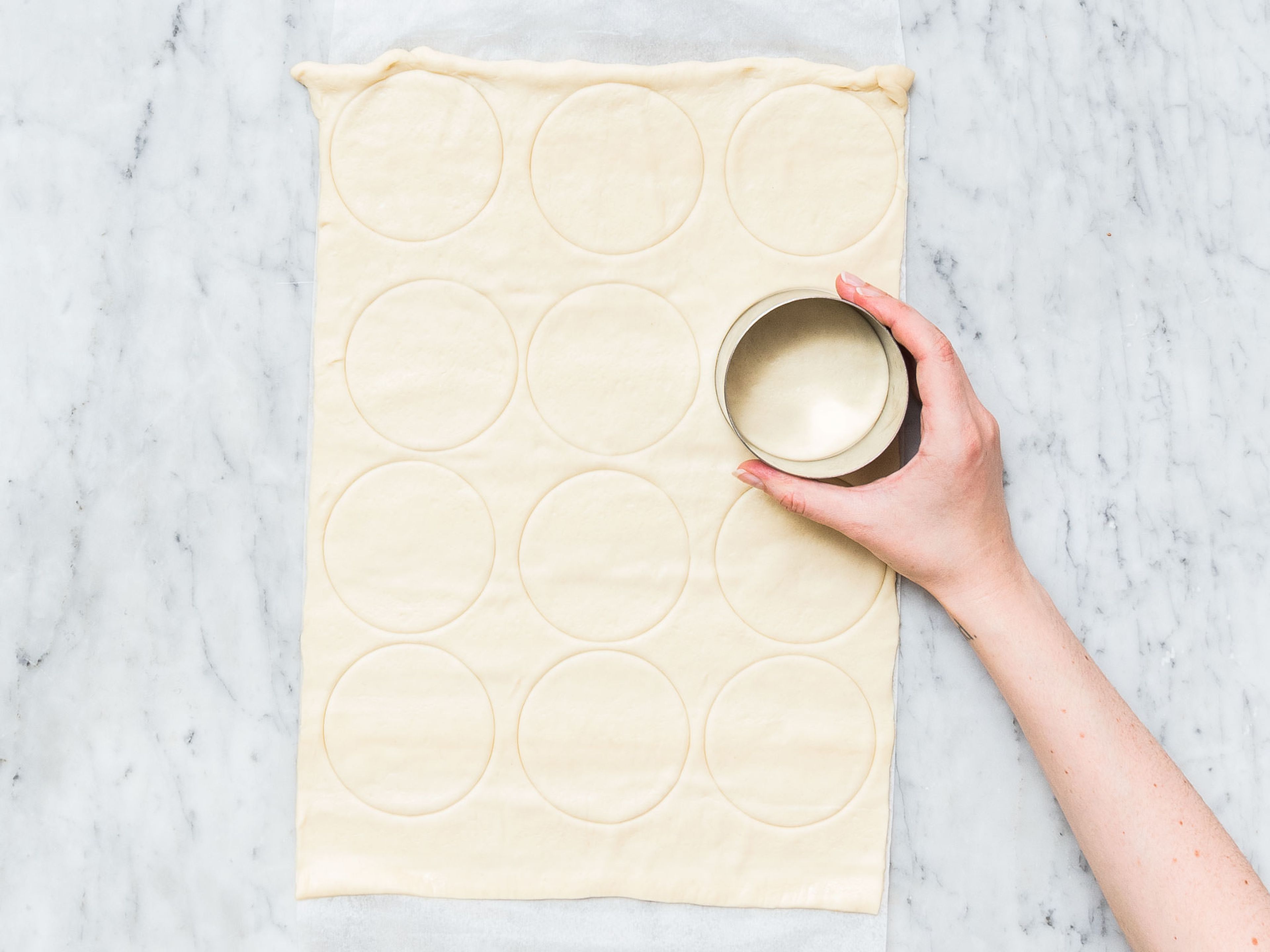 Slice tomatoes and grate Gruyère cheese. Roll out pizza dough and an even number of equal-sized circles using the cookie cutter.