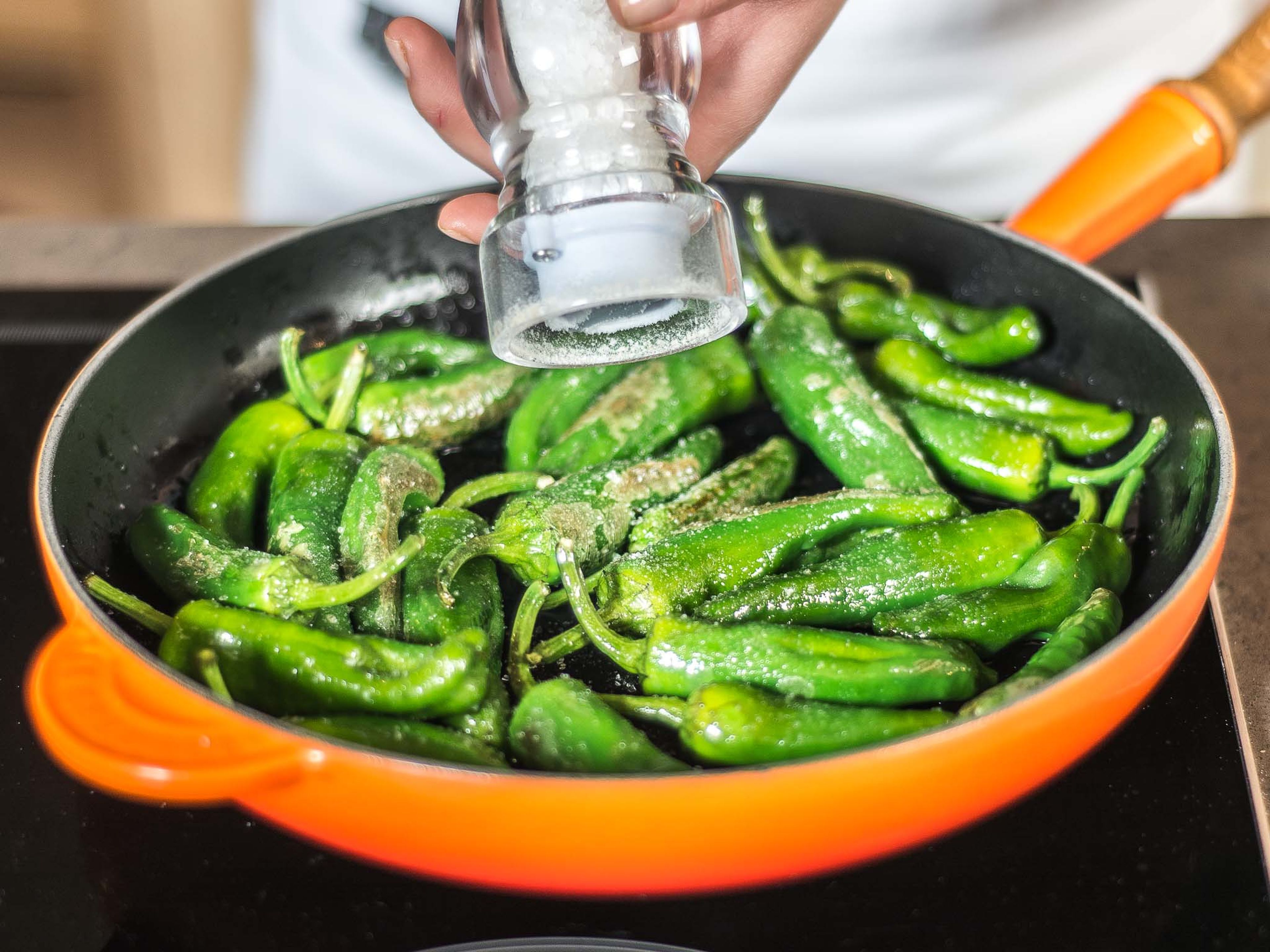 In a second pan, fry Padrón peppers in some vegetable oil and add plenty of salt. Toss the noodles in the sauce and serve in a deep dish with the fried Padrón peppers on top.