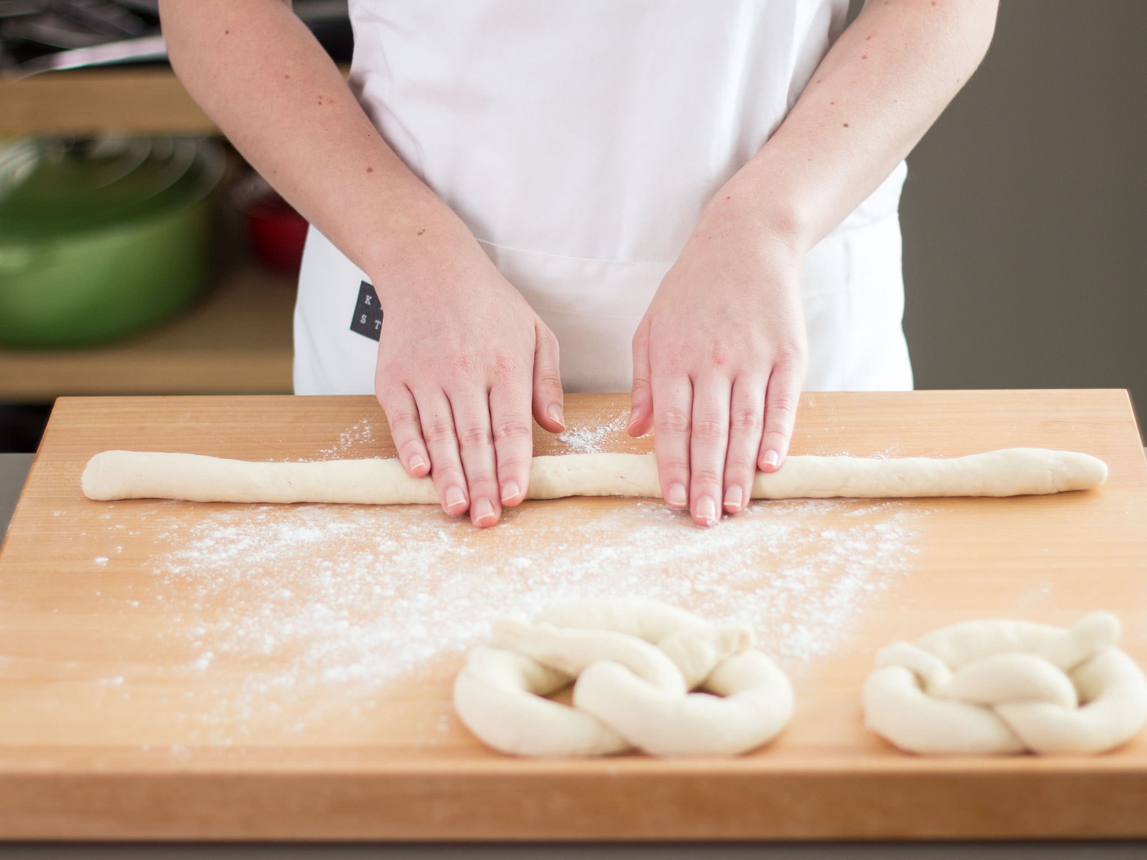 Preheat oven to 200°C/400°F. On a lightly floured surface, knead the dough once more and divide into ten portions. Roll each into long strips and fold into a pretzel shape.