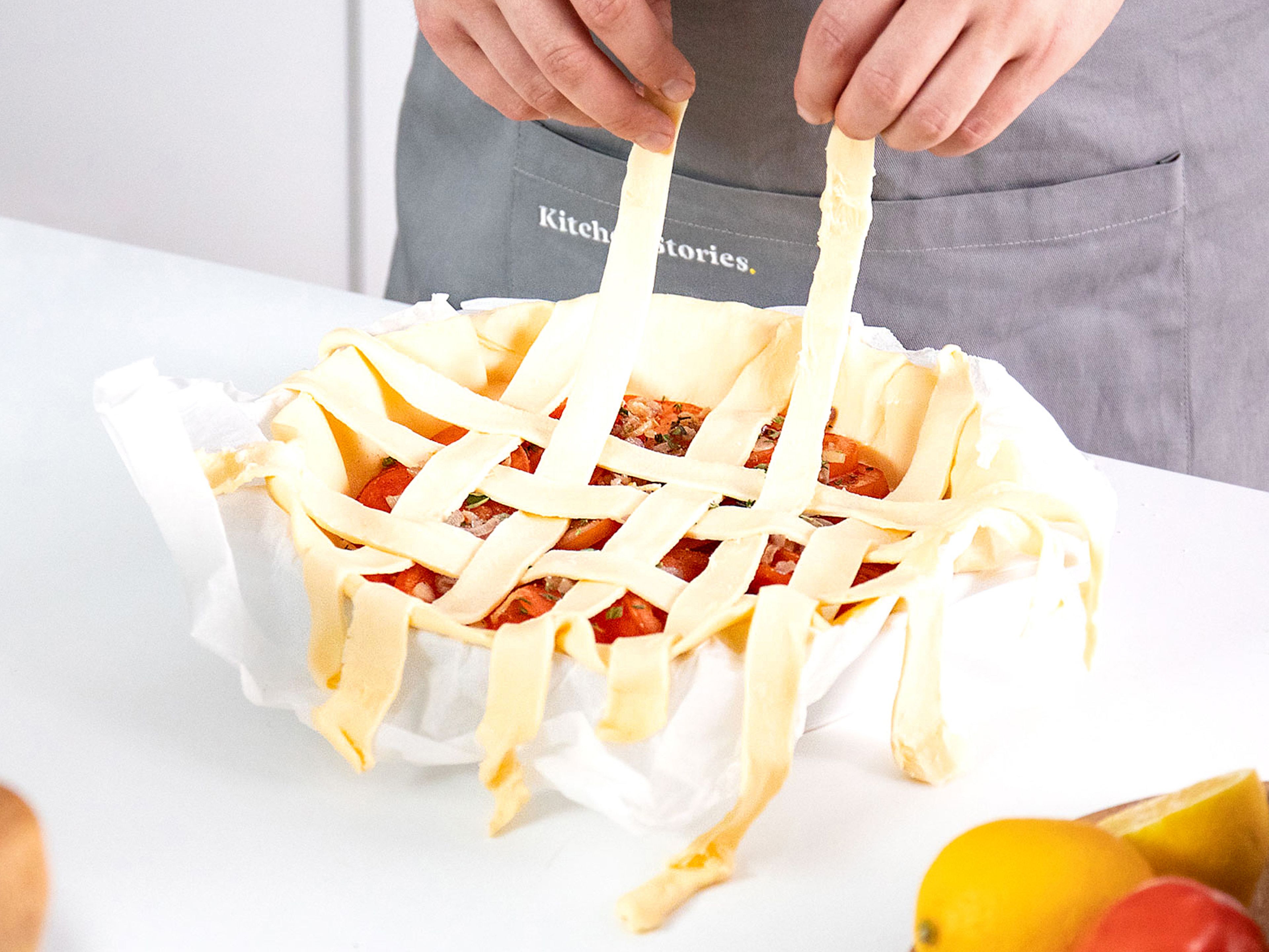 Cut the second sheet puff pastry into approx. 1 ¼ cm/½ in. wide strips. Layer the strips to form a lattice pattern over the pie. Now trim both pastry sheets, leaving approx. 1 ¼ cm/½ in. of dough hanging over the sides. Press to seal the dough together and wrap it up around the edges.