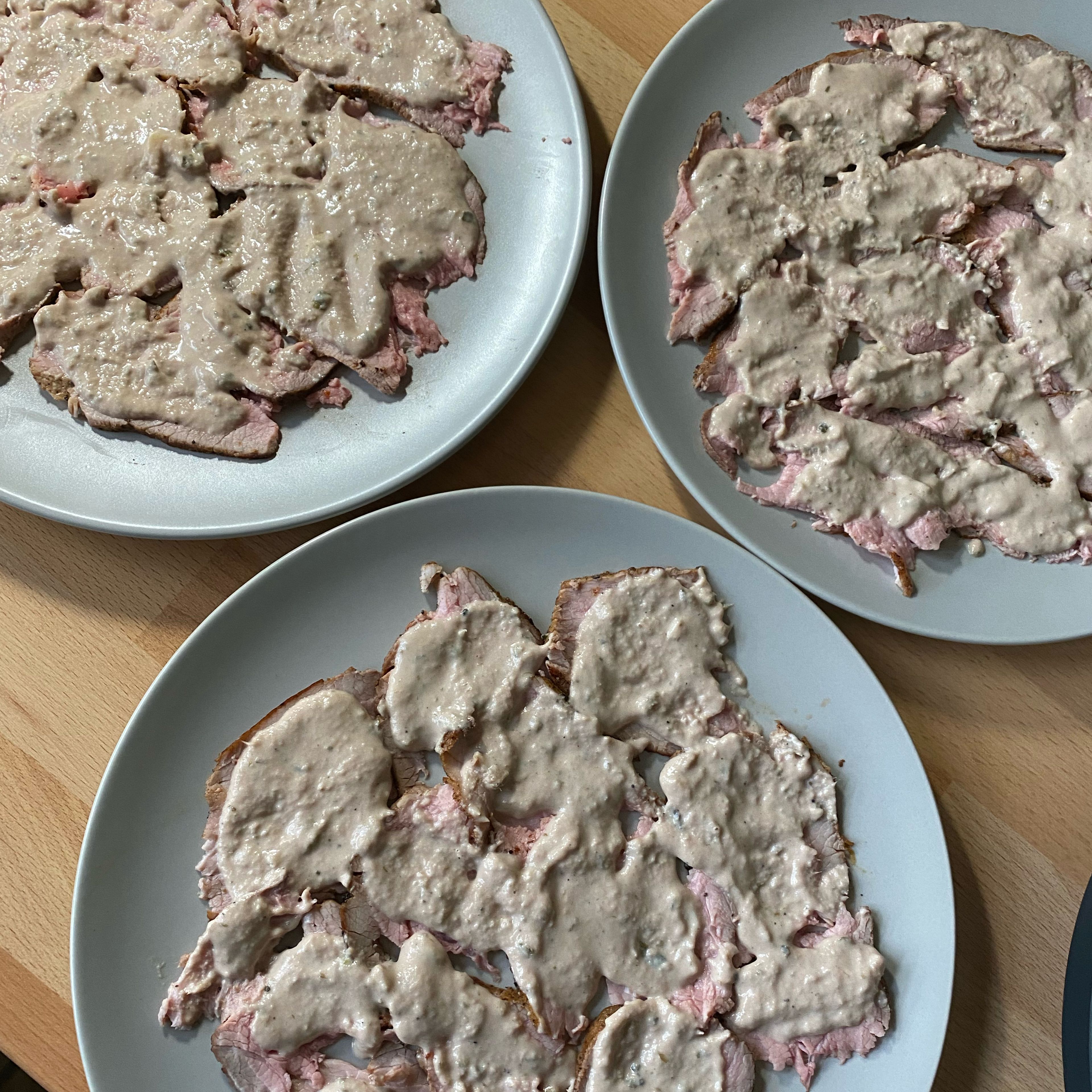 Jetzt wird die Thunfischsoße über das Fleisch gestrichen. So sollten die Teller mindestens 15 Minuten ruhen, bevor es an das Topping geht.