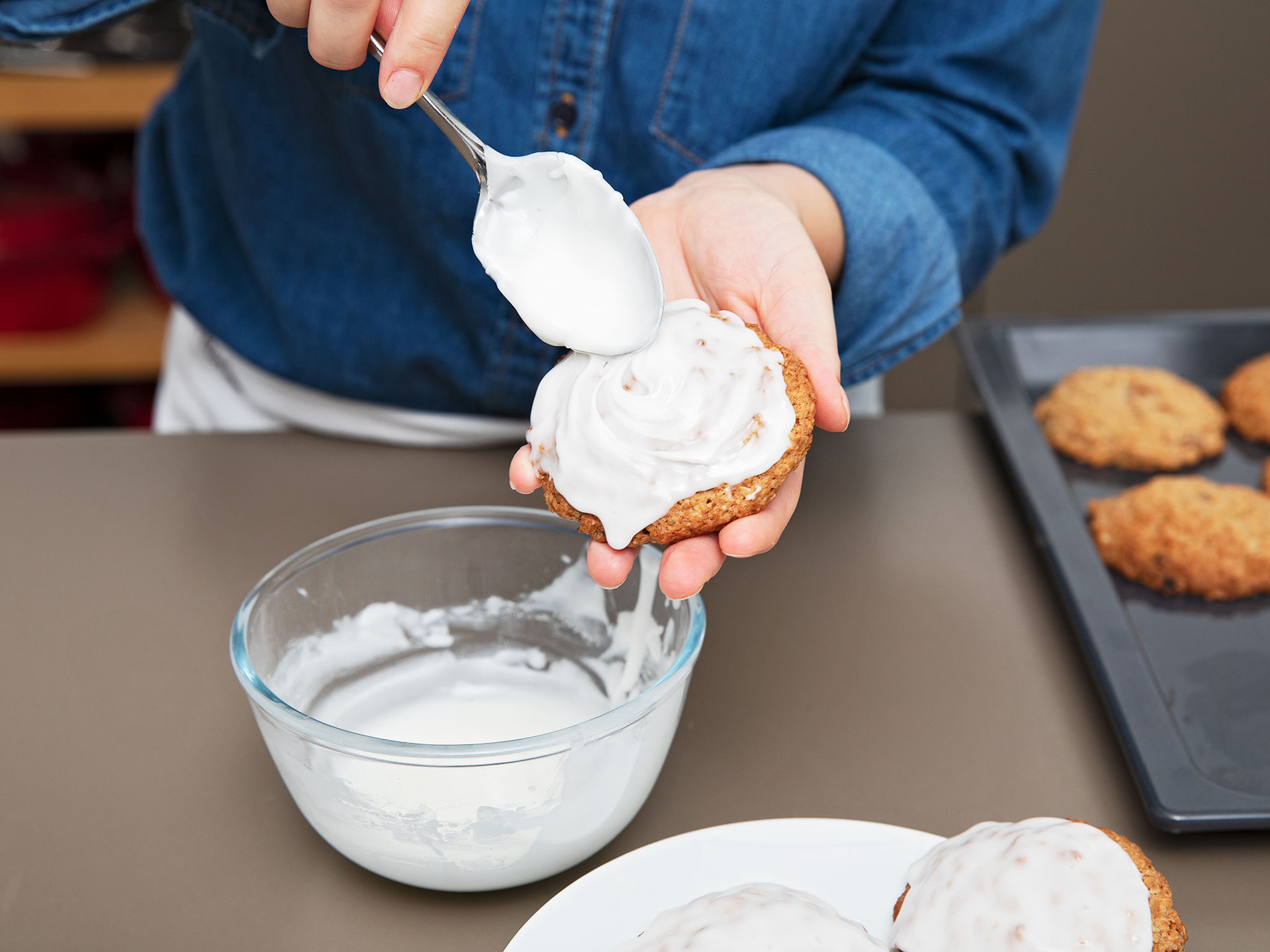 Ein Backblech mit Backpapier auslegen und den Keksteig mit einem Eisportionierer darauf portionieren. Zwischen jeder Teigkugel Platz lassen, da sie beim Backen auseinandergehen. Bei 190°C ca. 10 Min. backen. Anschließend komplett auskühlen lassen. Währenddessen den Zuckerguss zubereiten. Puderzucker, Milch und eine Prise Salz verrühren. Die Oberseite der Haferkekse vorsichtig in den Zuckerguss tunken und die Kekse ca. 30 Min. trocknen lassen. Guten Appetit!