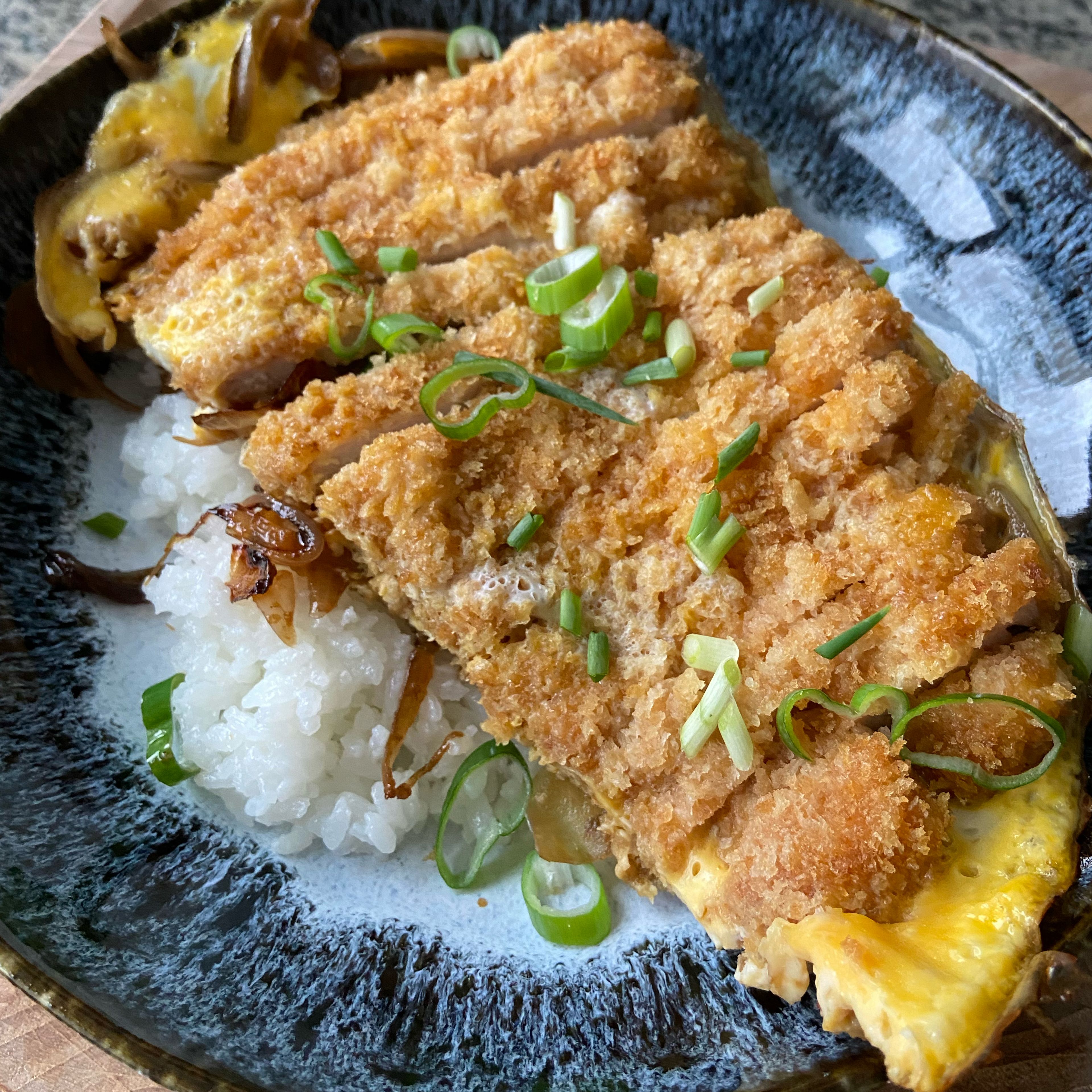 Plate each rice portion and divide the cutlet/egg mixture in half and gently transfer each to sit atop the rice. Garnish with sliced scallions and enjoy!