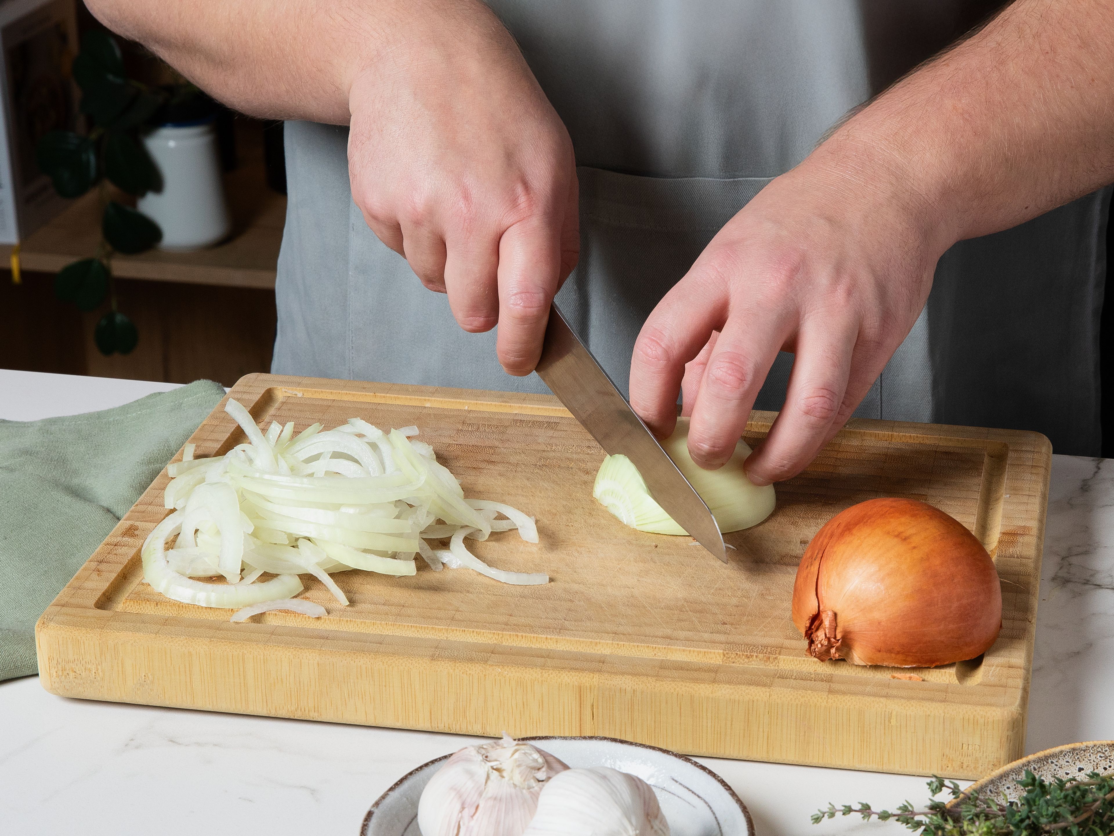 Die Zwiebeln und den Knoblauch schälen. Knoblauch fein hacken und beiseitestellen, die Zwiebeln so dünn wie möglich in feine Halbmonde schneiden. In einer großen Pfanne Butter und Olivenöl erhitzen. Sobald die Butter geschmolzen ist, die geschnittenen Zwiebeln hinzufügen und bei niedriger bis mittlerer Hitze ca. 30–40 Min. unter gelegentlichem Rühren weich kochen und karamellisieren lassen.