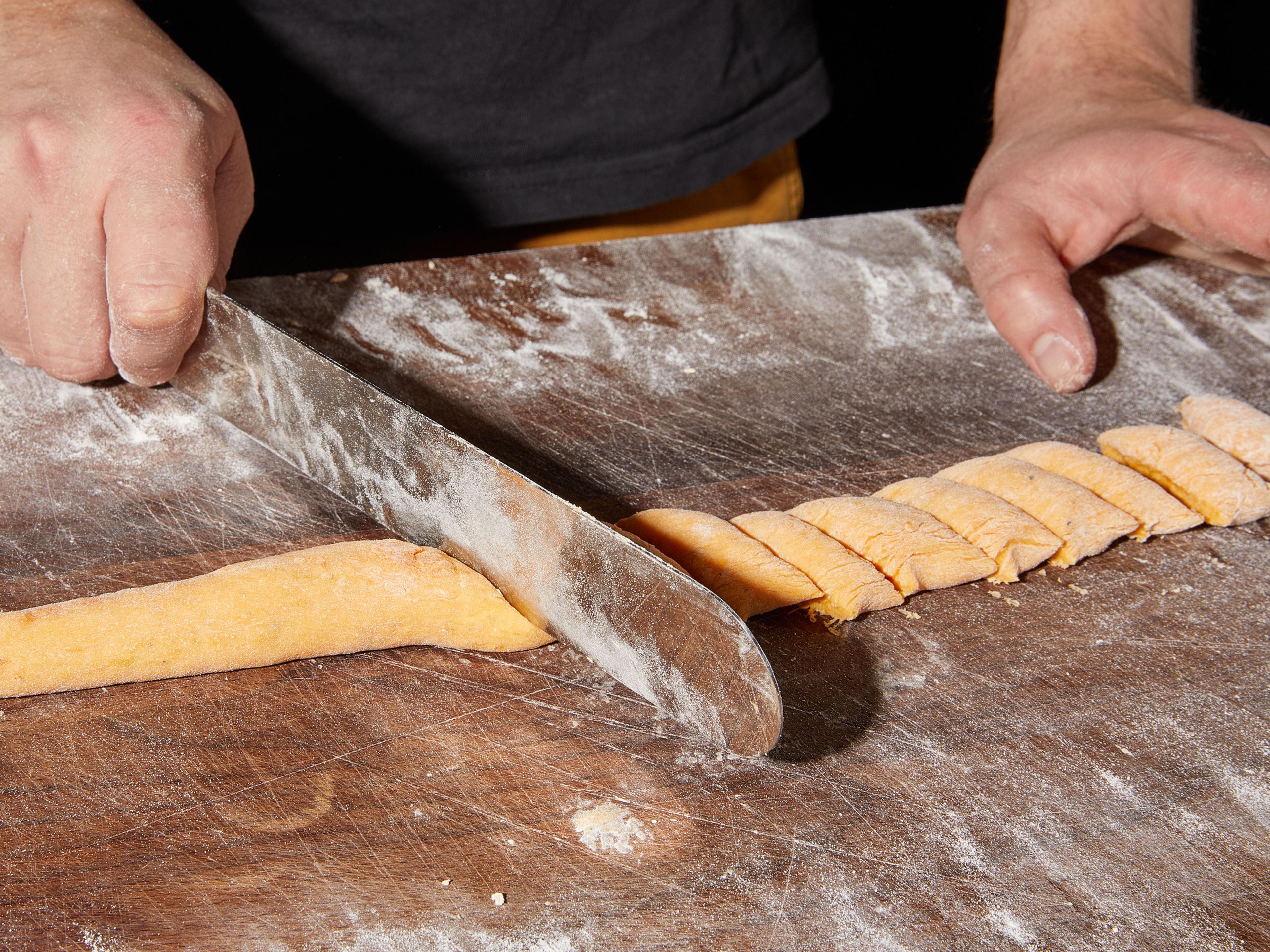 Cut the dough into four even pieces with a bench scraper. Dust work surface and hands with flour and roll each piece of dough into a rope, approx. 1/2 – 1 in. thick. Cut the strand into bite-sized pieces. Do not forget to flour your tools and the work surface regularly.