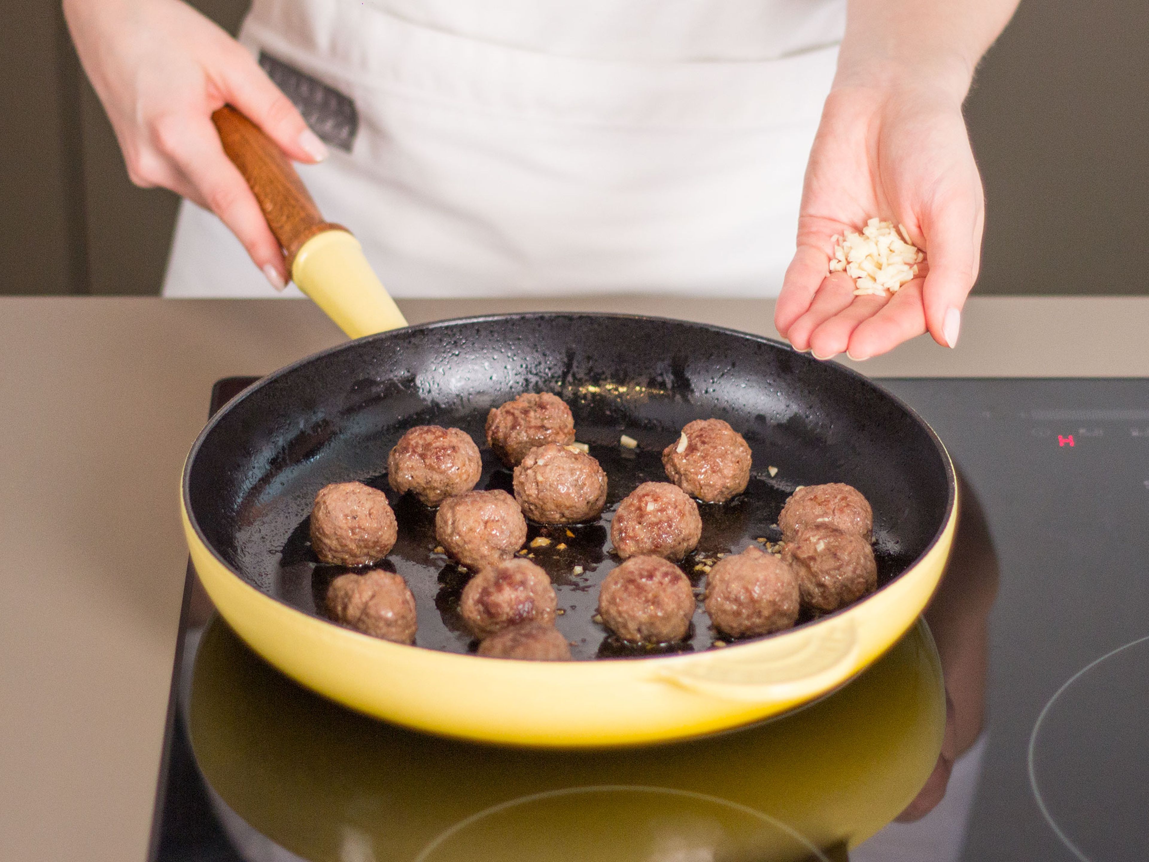 Season ground beef to taste with salt and pepper and form into ping pong-sized meatballs. Heat up some vegetable oil in a large frying pan over medium heat. Add meatballs and cook for approx. 4 – 6 min. until browned. Add garlic once meatballs are nearly cooked through.
