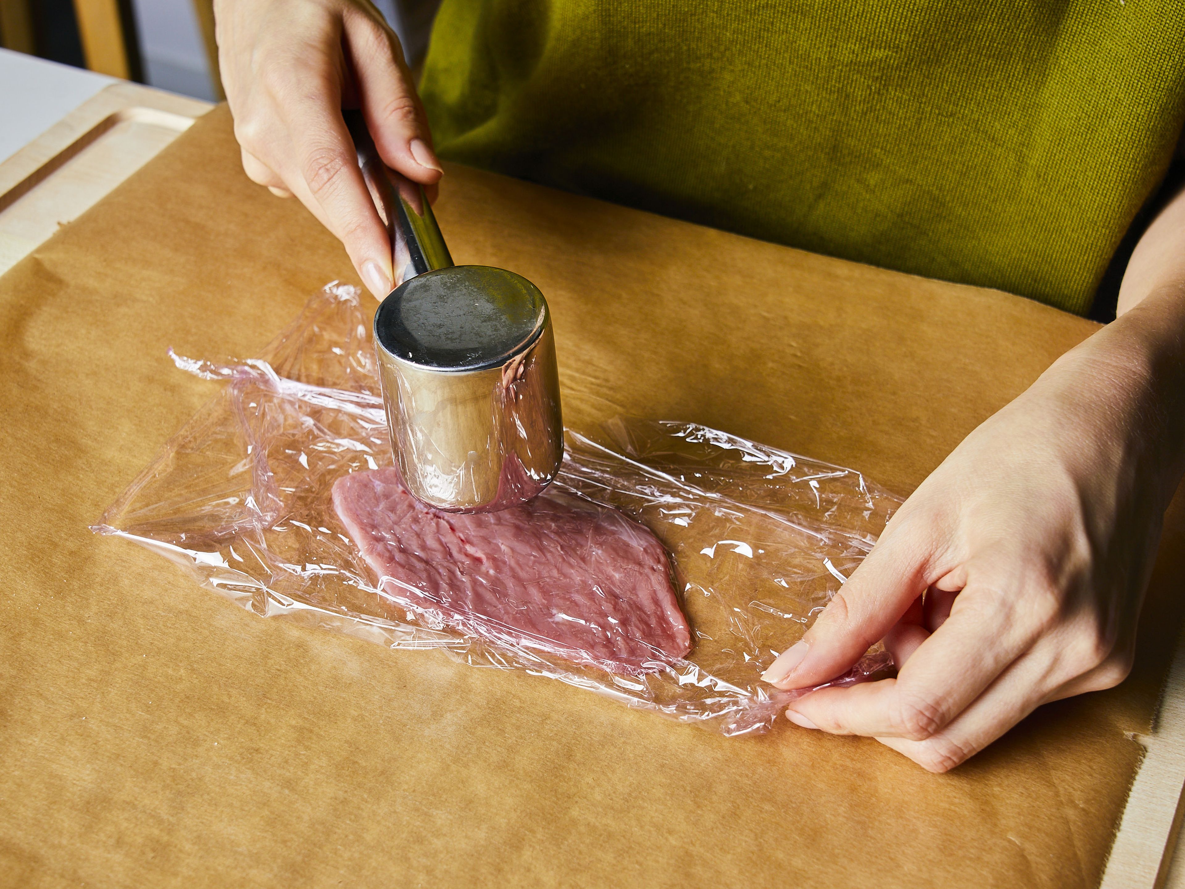 Cut veal cutlets into portions. Prepare a sheet of plastic wrap on a working surface, place the veal cutlets on top, and cover with plastic wrap. Flatten the cutlets using a meat tenderizer. Transfer to a plate and repeat with remaining veal cutlets.