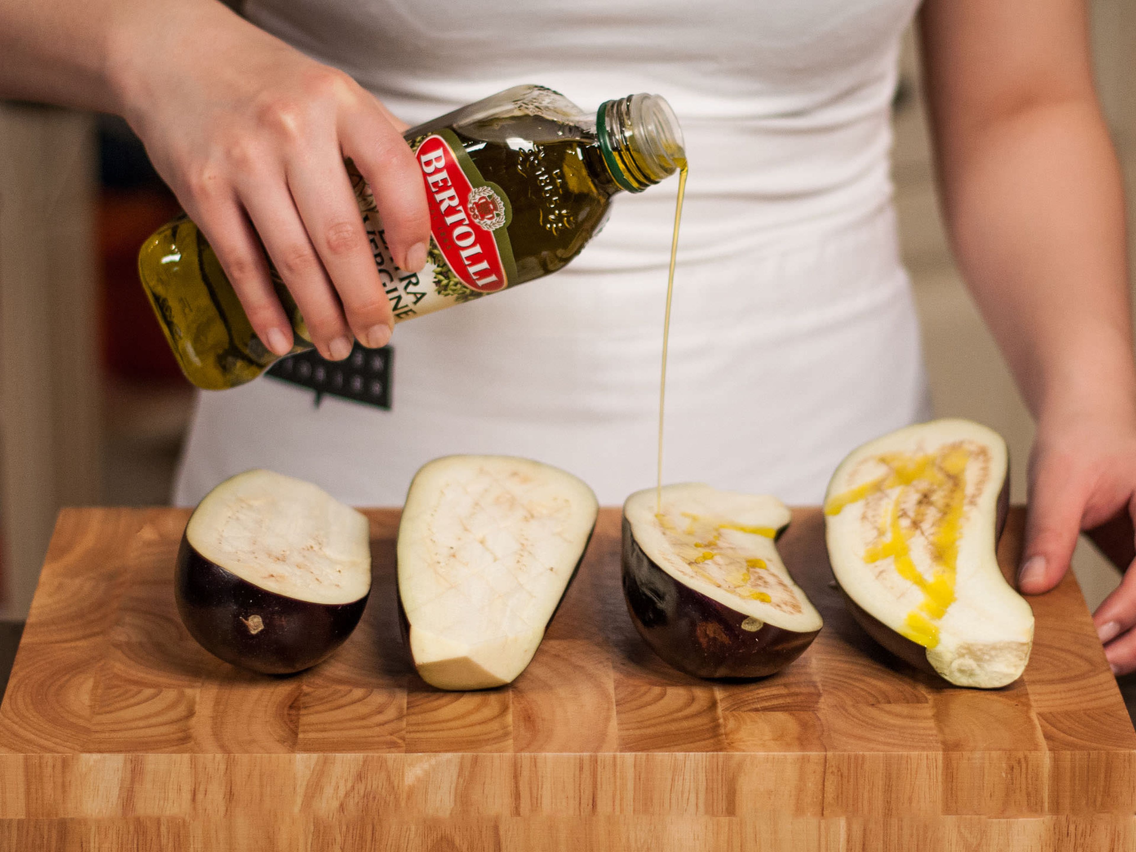 Backofen auf 200°C vorheizen. Auberginen halbieren, rautenförmig einschneiden und mit ca. 1/5 des Olivenöls beträufelt für ca. 30 – 40 Min. weich backen.