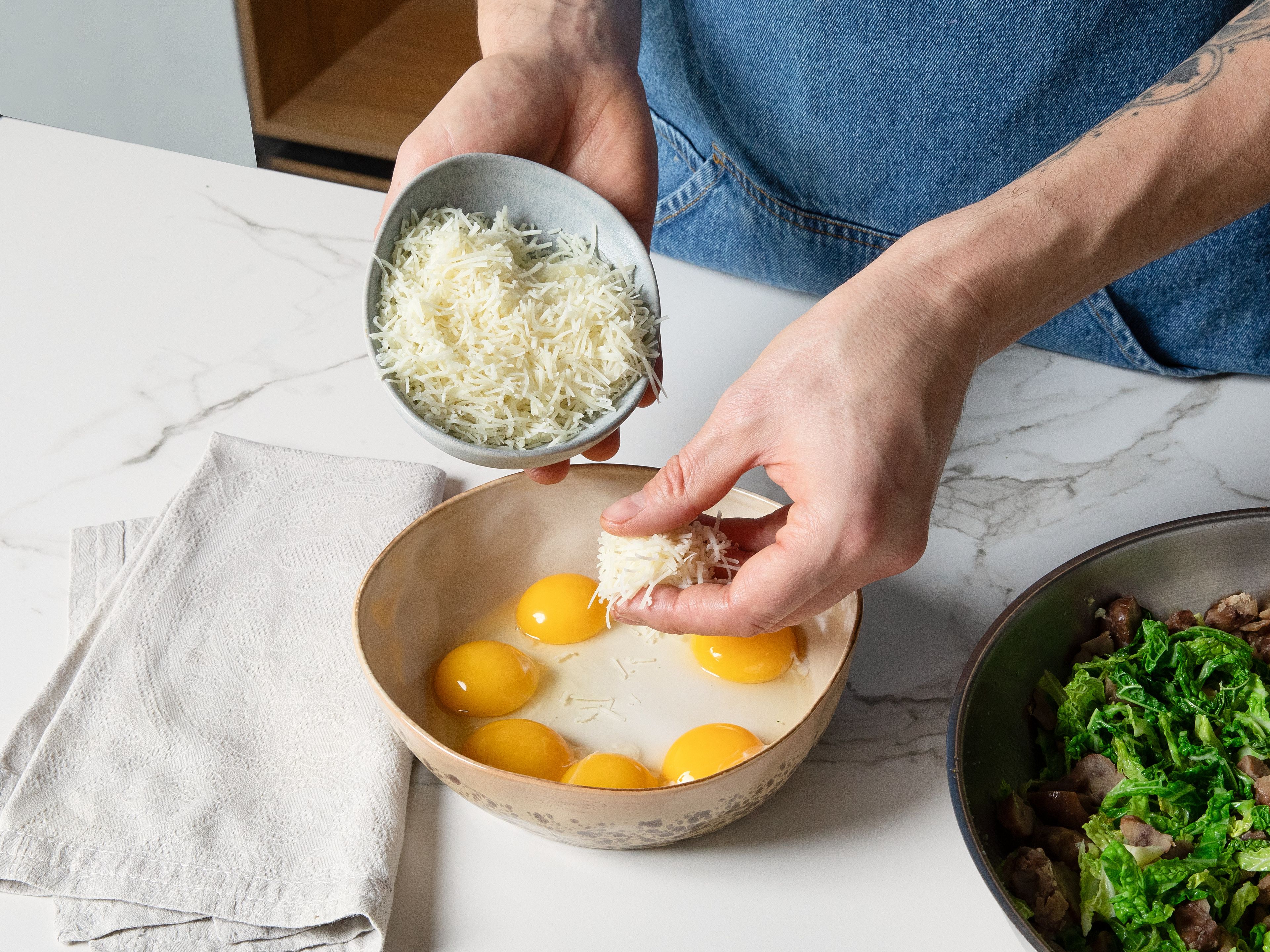In einer kleinen Schüssel Eigelbe mit dem restlichen geriebenen Pecorino und etwas frisch gemahlenem Pfeffer verrühren. Dann die Einmischung zusammen mit der Hälfte des beiseite gestellten Pastawassers in die Pfanne zur noch heißen Pasta geben. Alles schnell und gleichmäßig miteinander vermischen bis eine cremige Soße entsteht und bevor die Eier zu Rührei werden. Nach Bedarf mehr Pastawasser hinzufügen. Mit dem Pecorino-Crunch und etwas gehackter Petersilie bestreuen und sofort servieren.