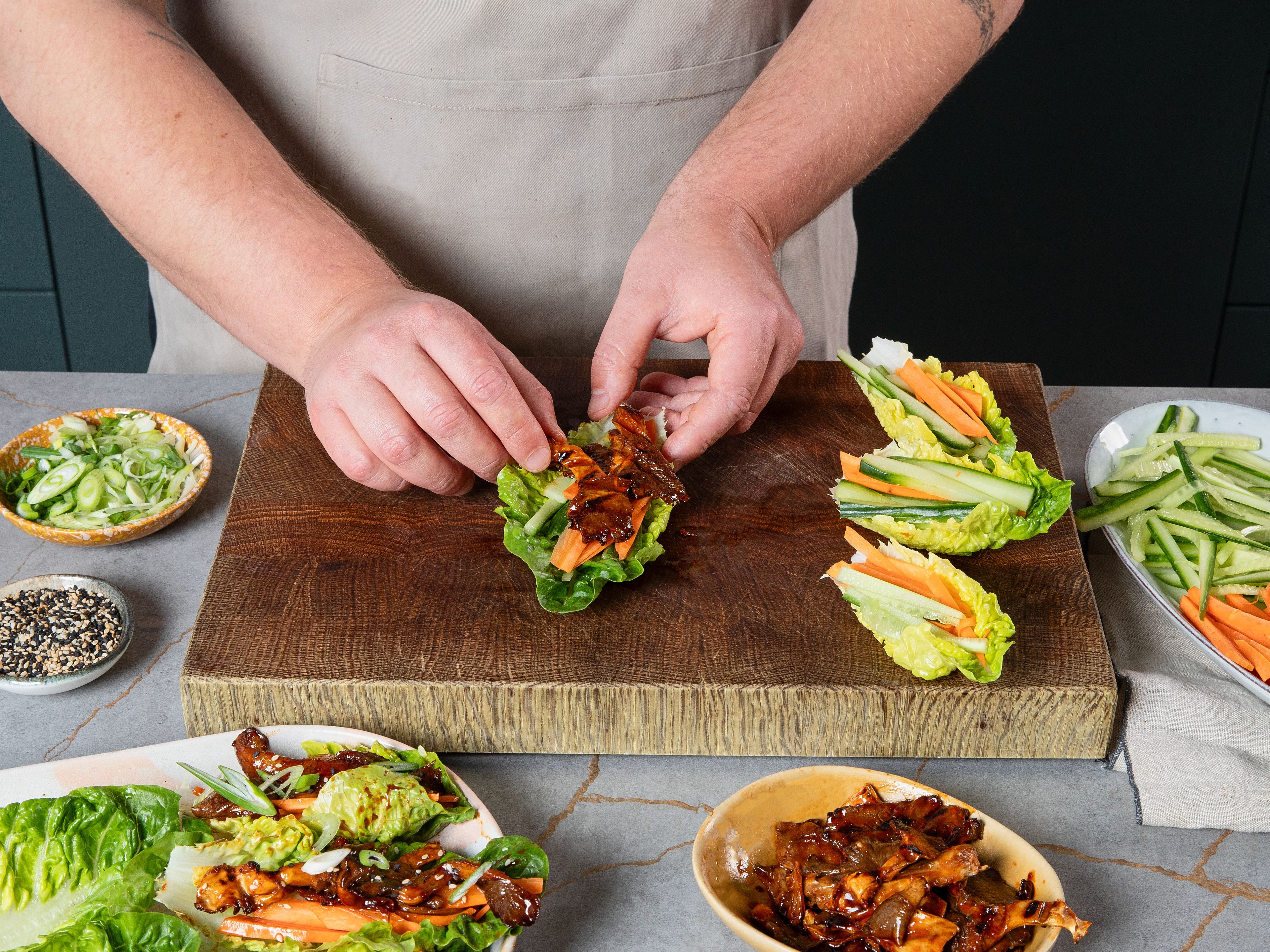 Die Salatblätter mit den gegrillten Austernpilzen, Karotte, Gurke und Kimchi füllen. Zum Servieren mit Sesam und den Frühlingszwiebeln garnieren.