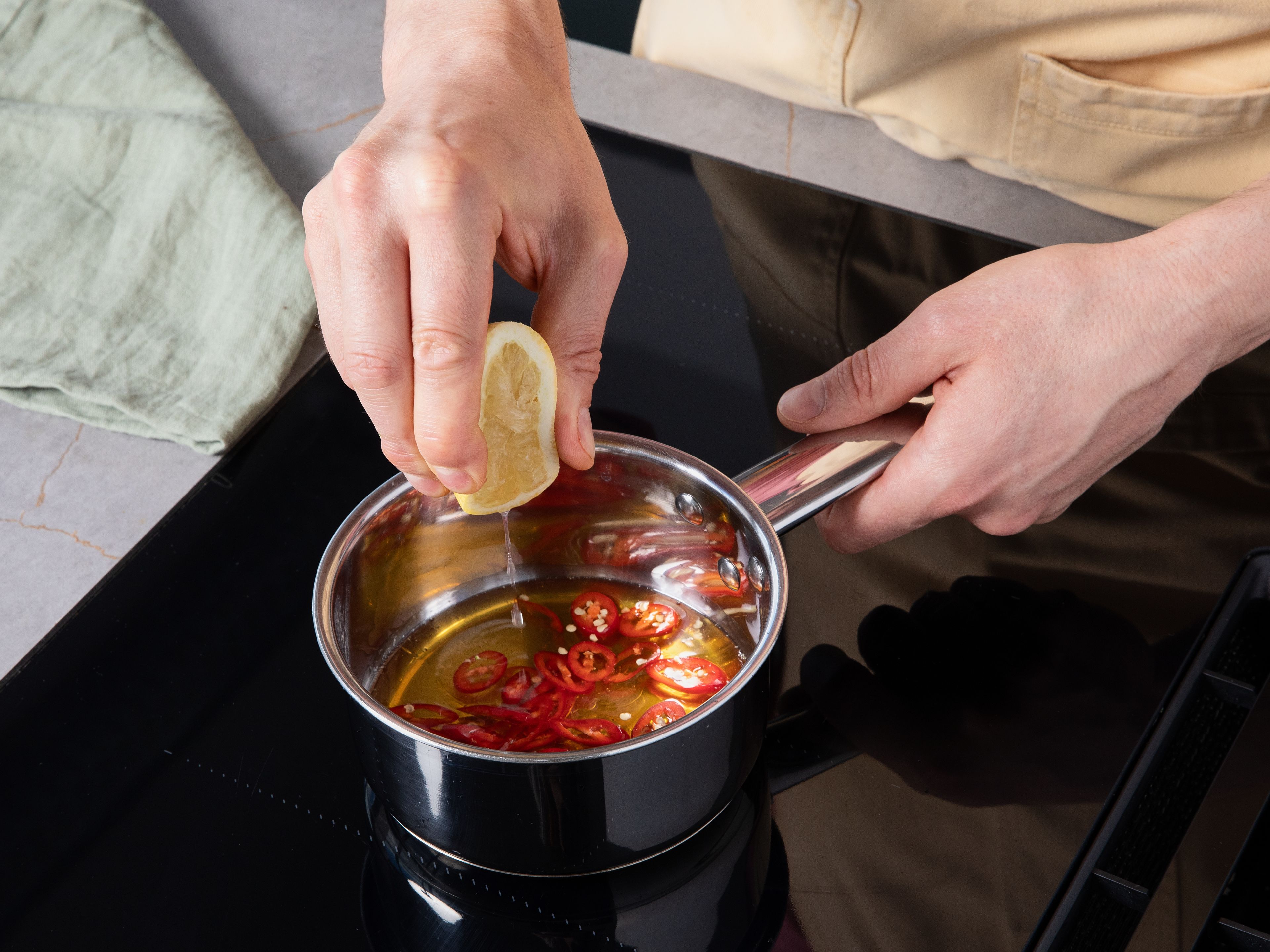 In der Zwischenzeit Chili in feine Ringe schneiden. Honig in einem kleinen Topf bei niedriger Hitze erwärmen, dann mit etwas Zitronensaft und der Chili verrühren. Mit Salz und Pfeffer abschmecken. Feta grob zerbröseln.