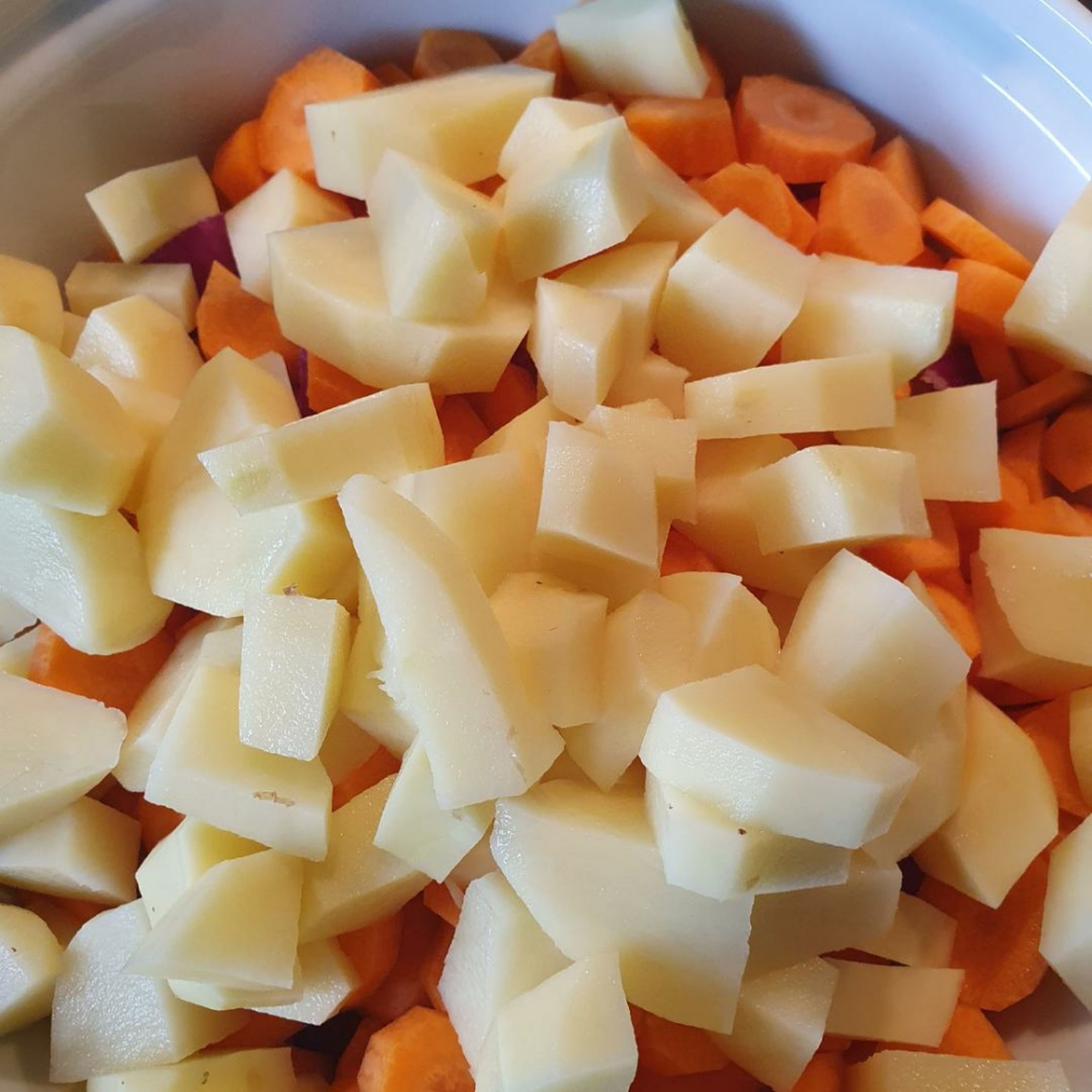 Zwiebeln in grobe Stücke schneiden. Karotten in Scheiben schneiden. Kartoffeln würfeln. Alles zusammen in den Topf zum Fleisch geben.