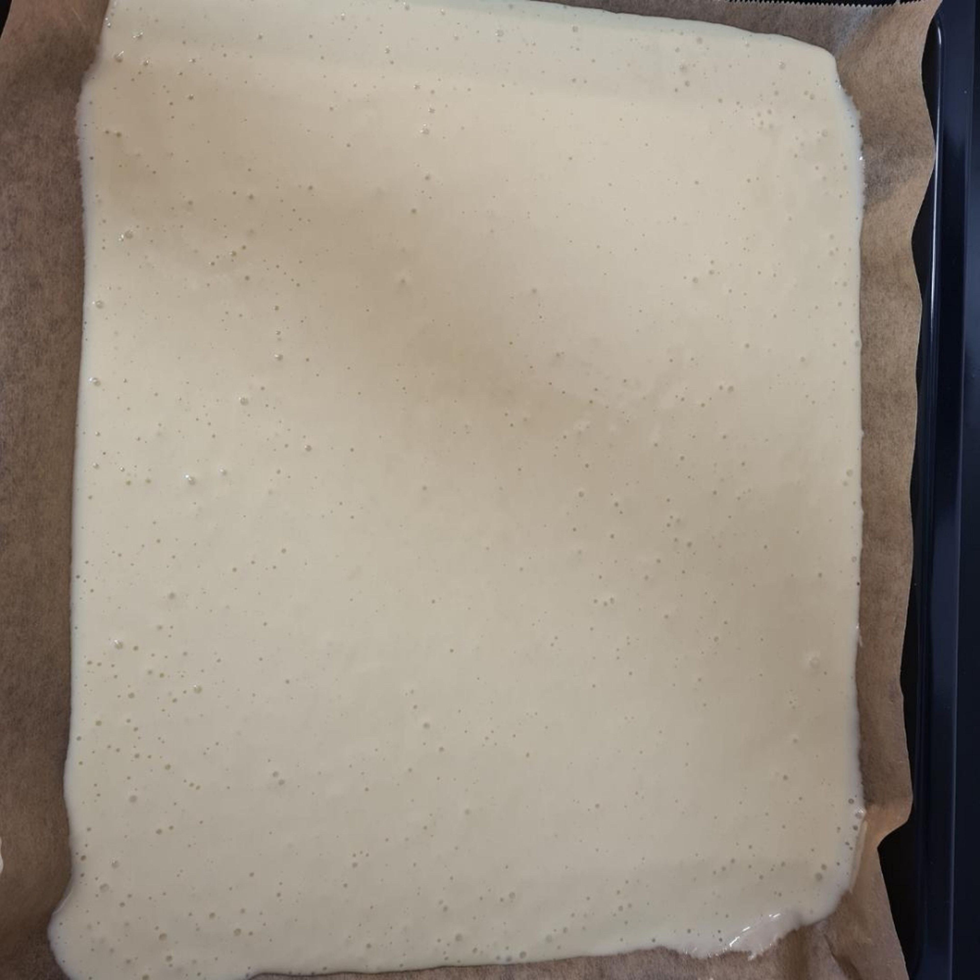 Teig auf ein mit Backpapier belegtes Backblech geben und verteilen.