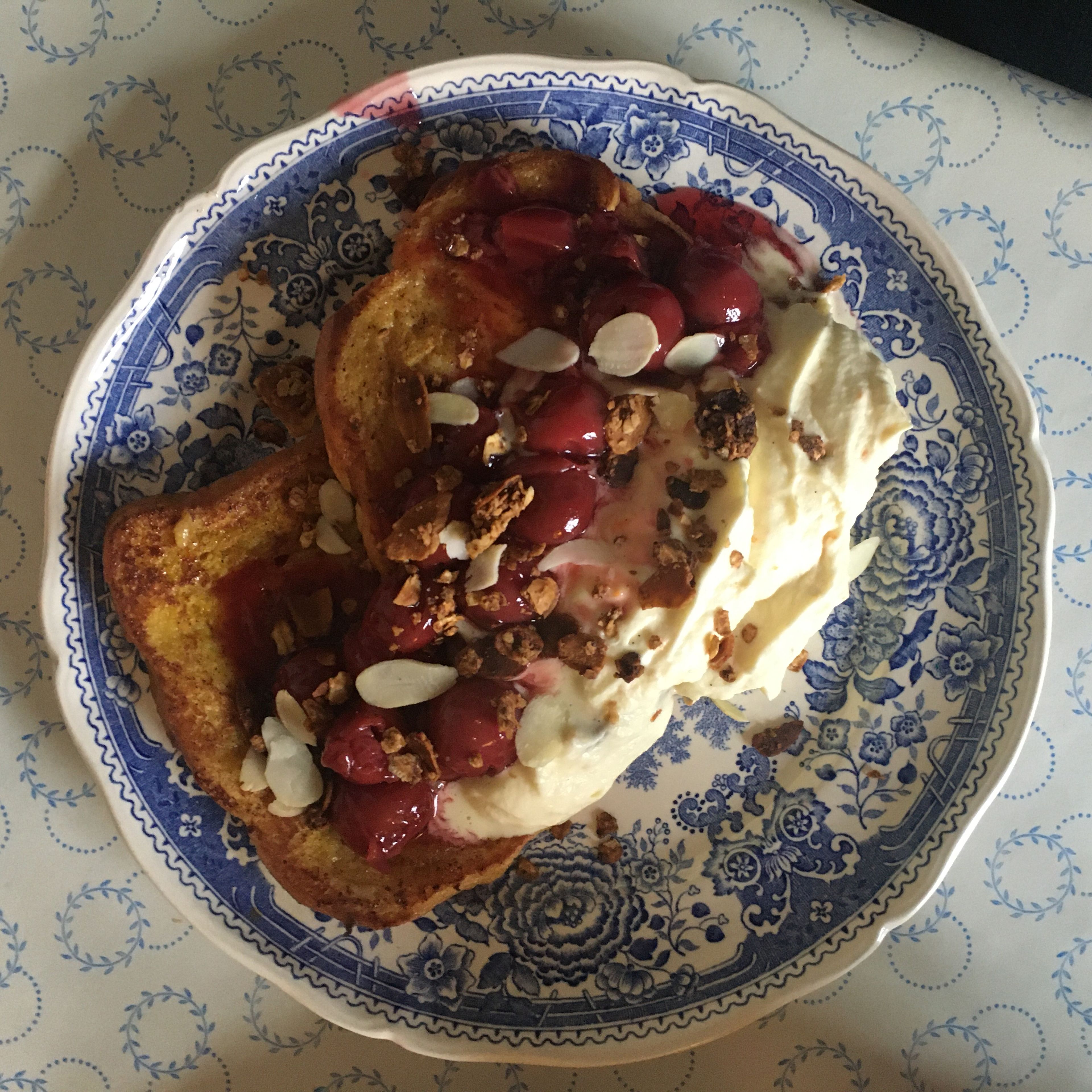 Lay two slices of french toast on a plate, pour a spoon of cream and cherries over and sprinkle the crunch around it. Garnish with mint to make it extra fancy.